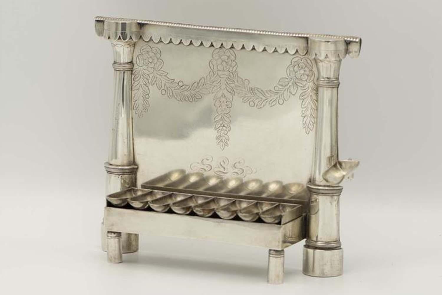 Handmade silver Hanukkah Lamp Menorah,Lemberg, Germany, circa 1770.
Of a bench form with opened oil fonts, on cylindrical feet, the backplate is engraved with flowers, leaves and the owner's name initials.
Bordered by pair of 