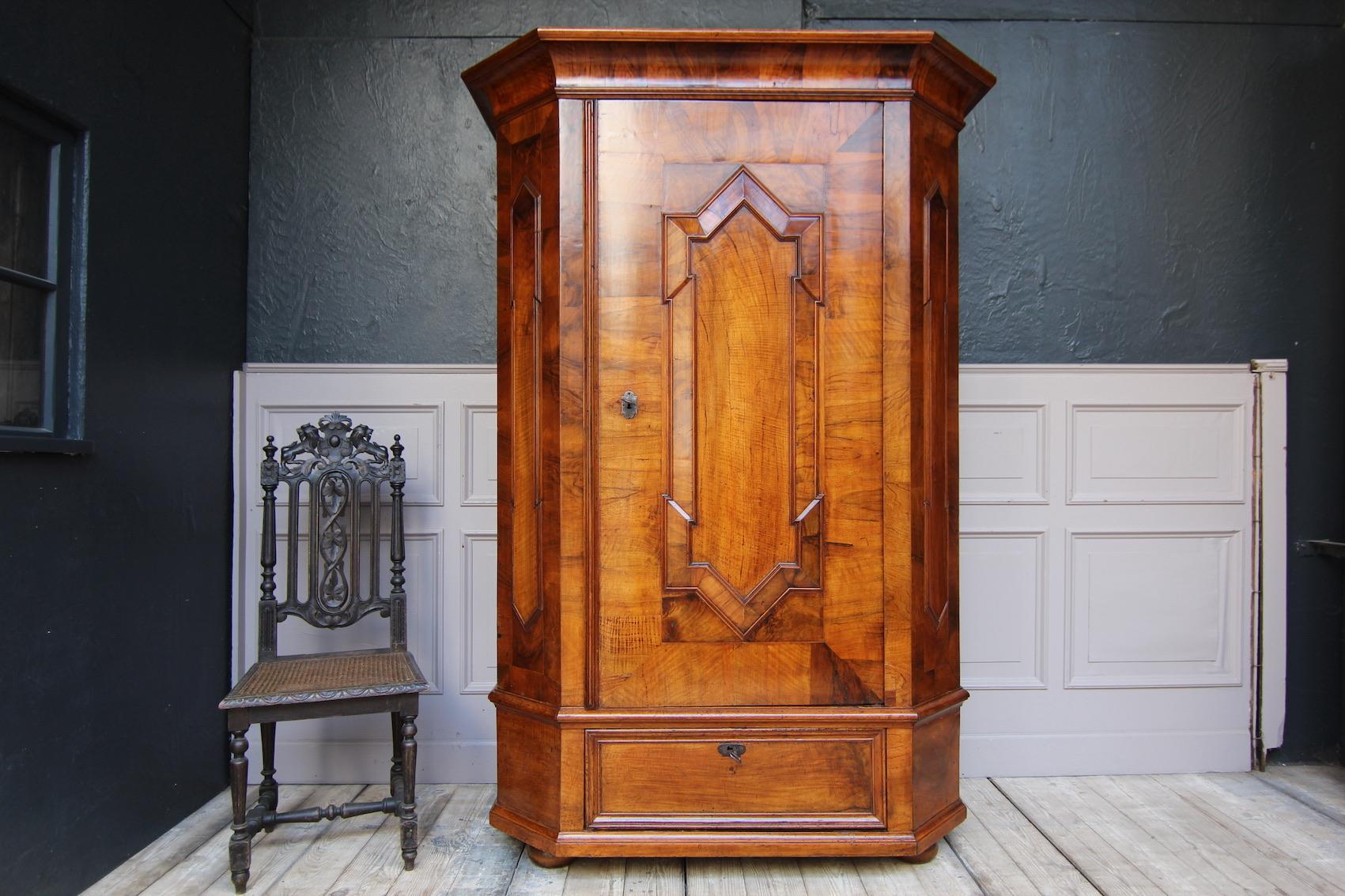 Rare German single door baroque cabinet from around 1800. Mainly walnut and burl veneered on pine. 

Single door cabinet standing on squashed ball feet with pedestal drawer, chamfered corners and molded cornice.                                    