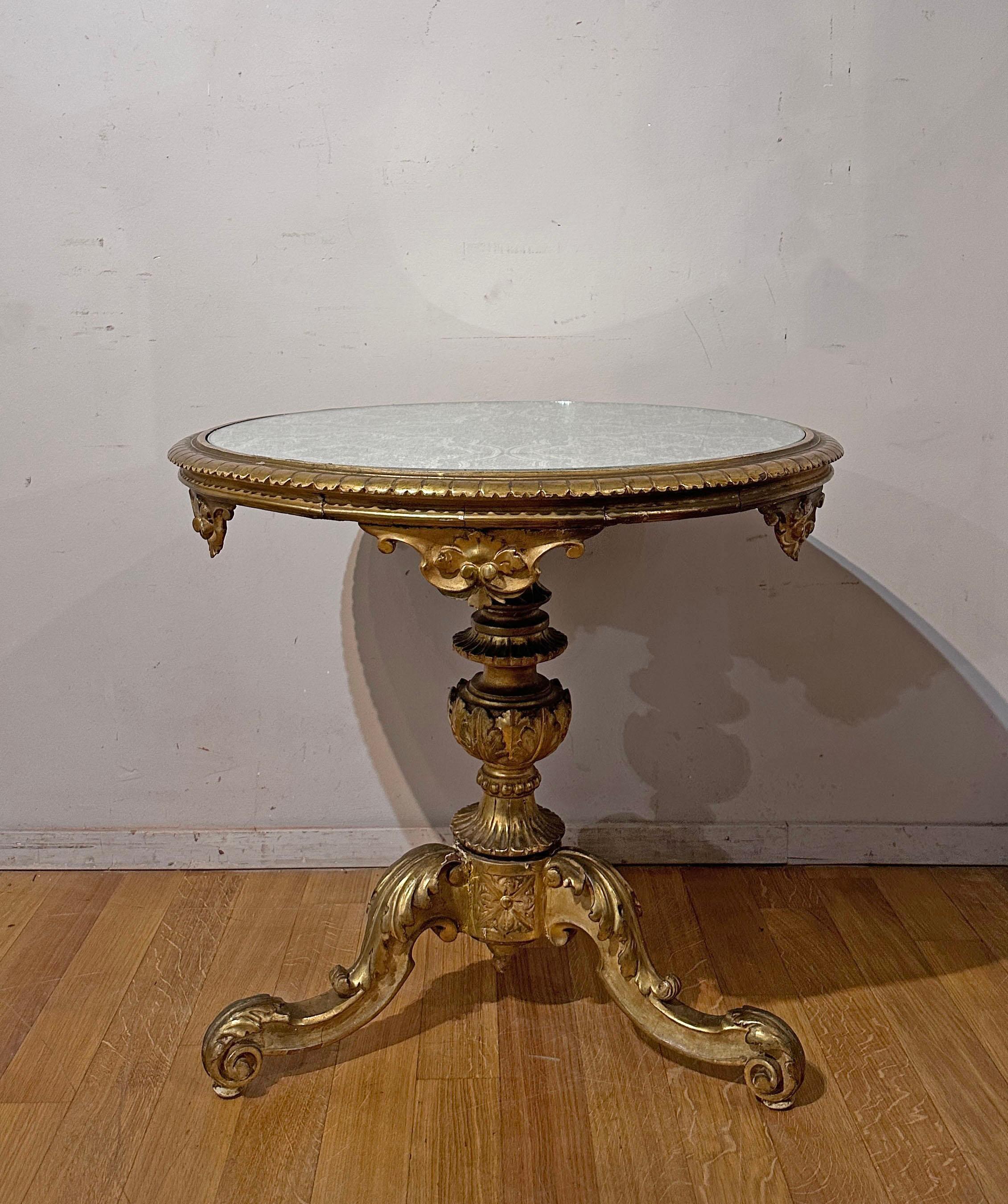 This tea table, made of fine carved wood and subsequently gilded with pure gold leaf, is an authentic masterpiece of design and craftsmanship. Characterized by a round fabric top, elegantly protected by glass, it is a true combination of