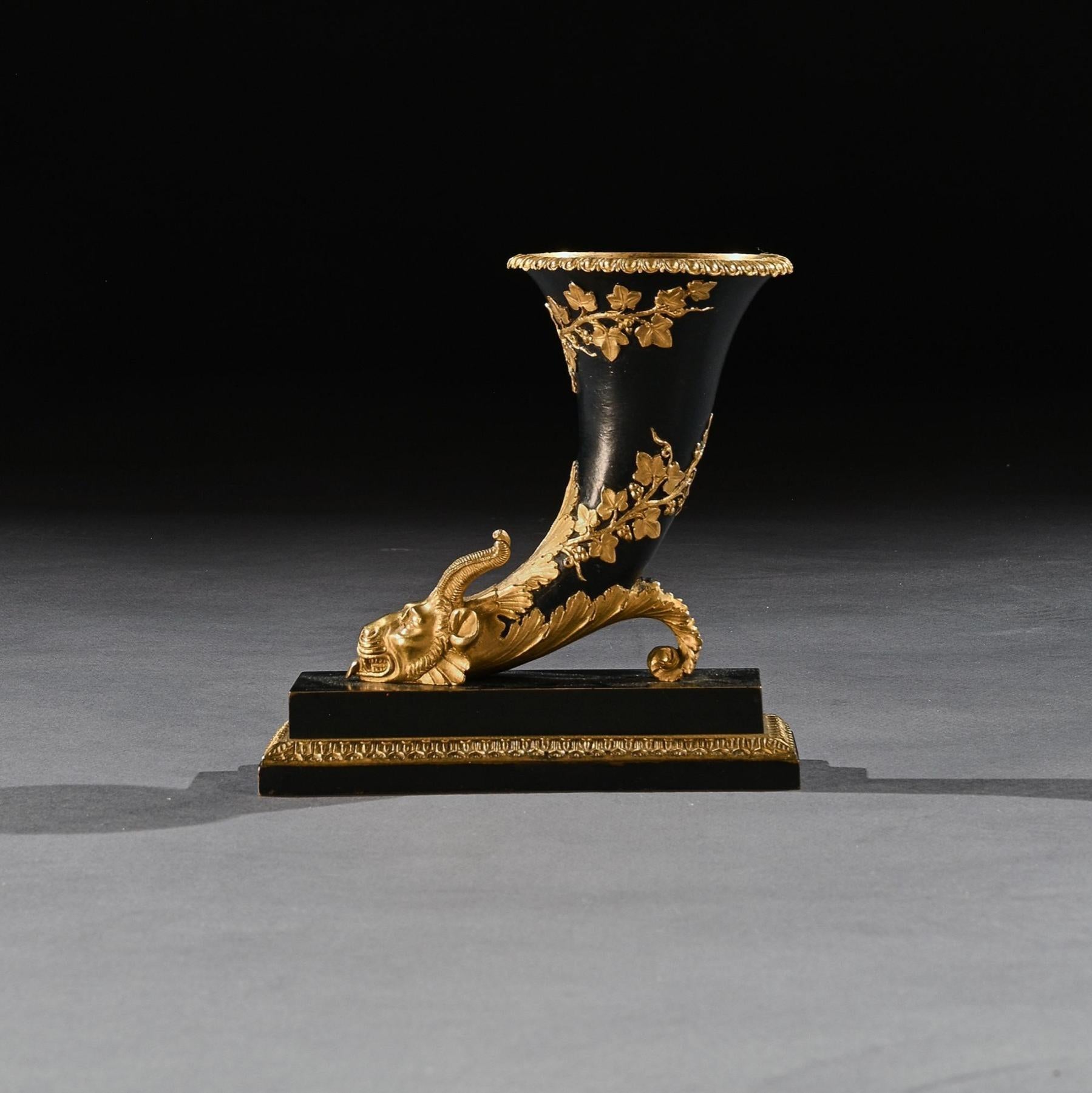 Extremely well cast and rare gilt and patinated Grand Tour bronze rhyton with chimera rams / lions head. 



French circa 1825.



The rhyton, of cornucopia form, being black patinated bronze with the head, foliage and rim gilt and partially
