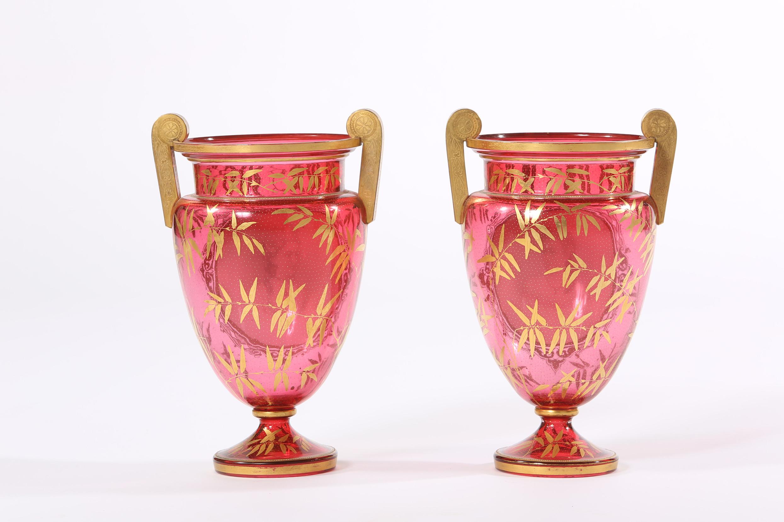 Coppia di vasi o urne in vetro dorato dell'inizio del XIX secolo con maniglie laterali. Ogni vaso è in ottime condizioni d'epoca, con un'usura coerente con l'età o l'uso. Ogni vaso è alto circa 11 pollici e ha un diametro di 8 pollici.