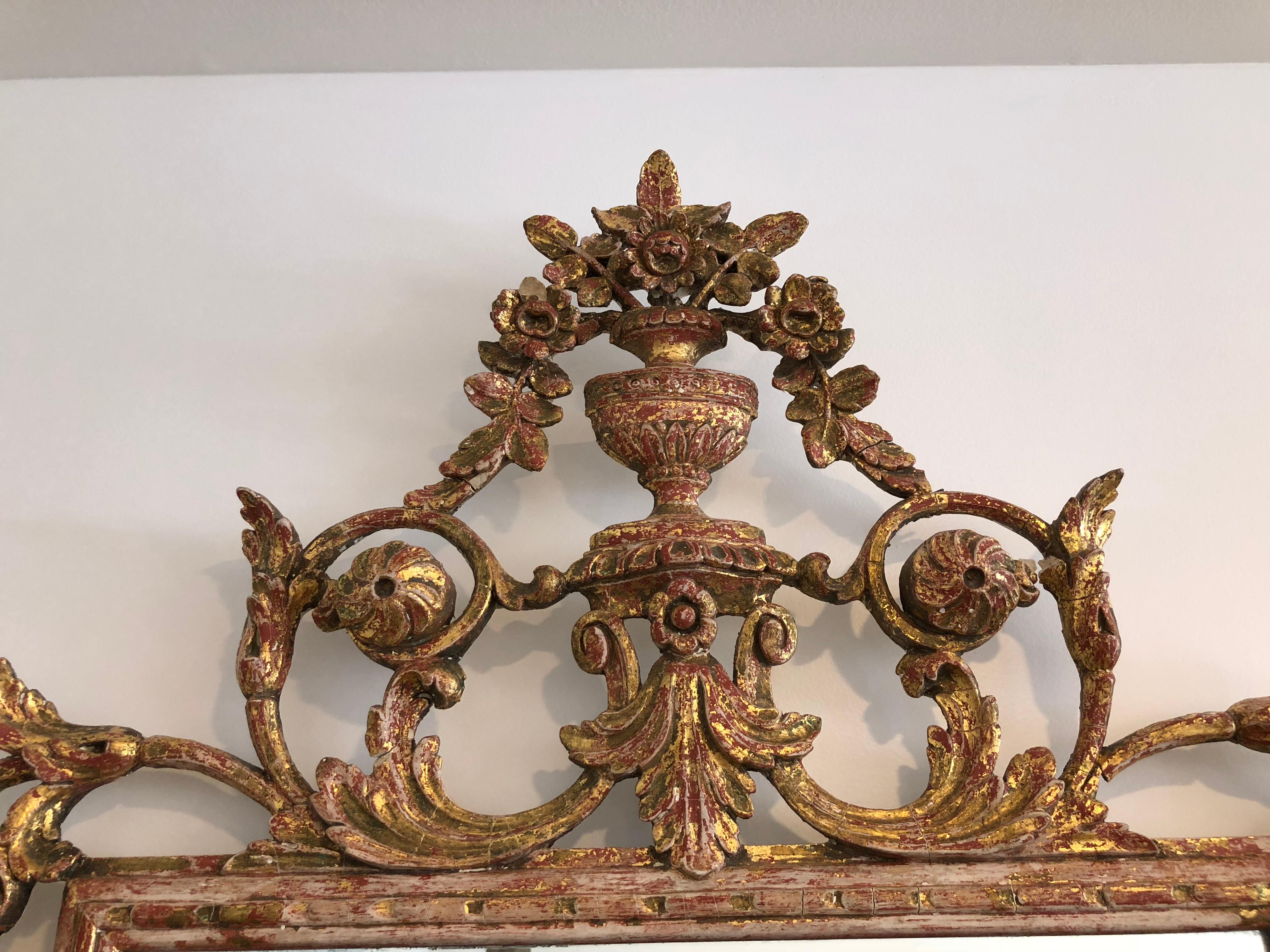 Highly decorative gilt mirror with clear glass and ornate gilt frame. Has some small worn areas consistent with its age. Very pretty piece with red highlights showing through the gilt.