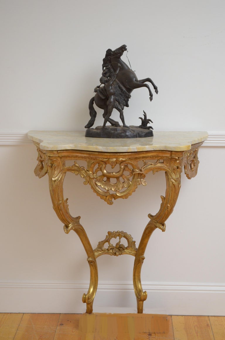 K0413 Attractive gilded console table of serpentine design, having original veined marble top above intricate frieze and 2 cabriole legs with foliage decoration, united by carved stretcher. This antique console is in home ready condition, circa