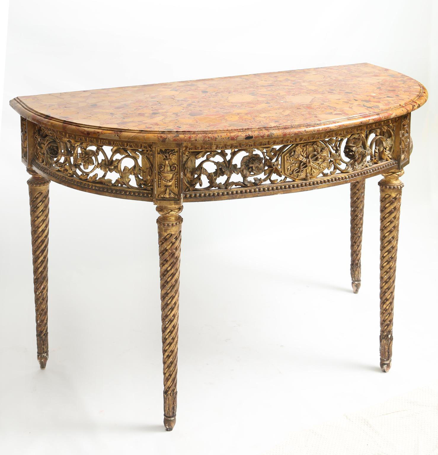 Console table, having a demilune form top of breche d'alep marble, its carved giltwood base having a central plaque of a quiver, crossed by Hermes' staff, flanked by laureling, its pierced, scrolling, foliate apron in a frame of gadrooning and