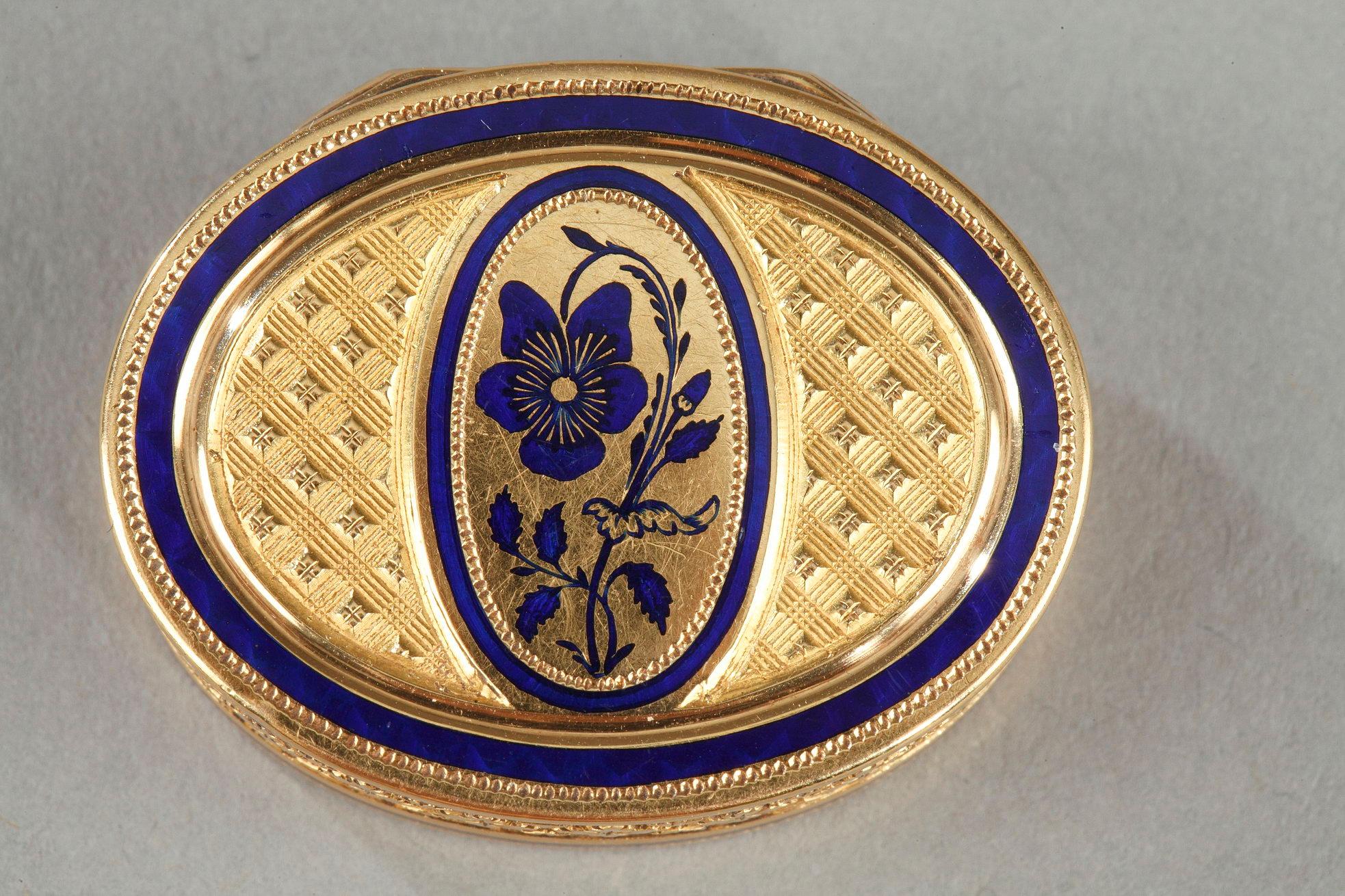 Oval-shaped gold and enamel vinaigrette. The vinaigrette is entirely decorated with a guilloche motif with stylized flower. The hinged lid is decorated in the center with a medallion with a violet in royal blue enamel on a matte background. The