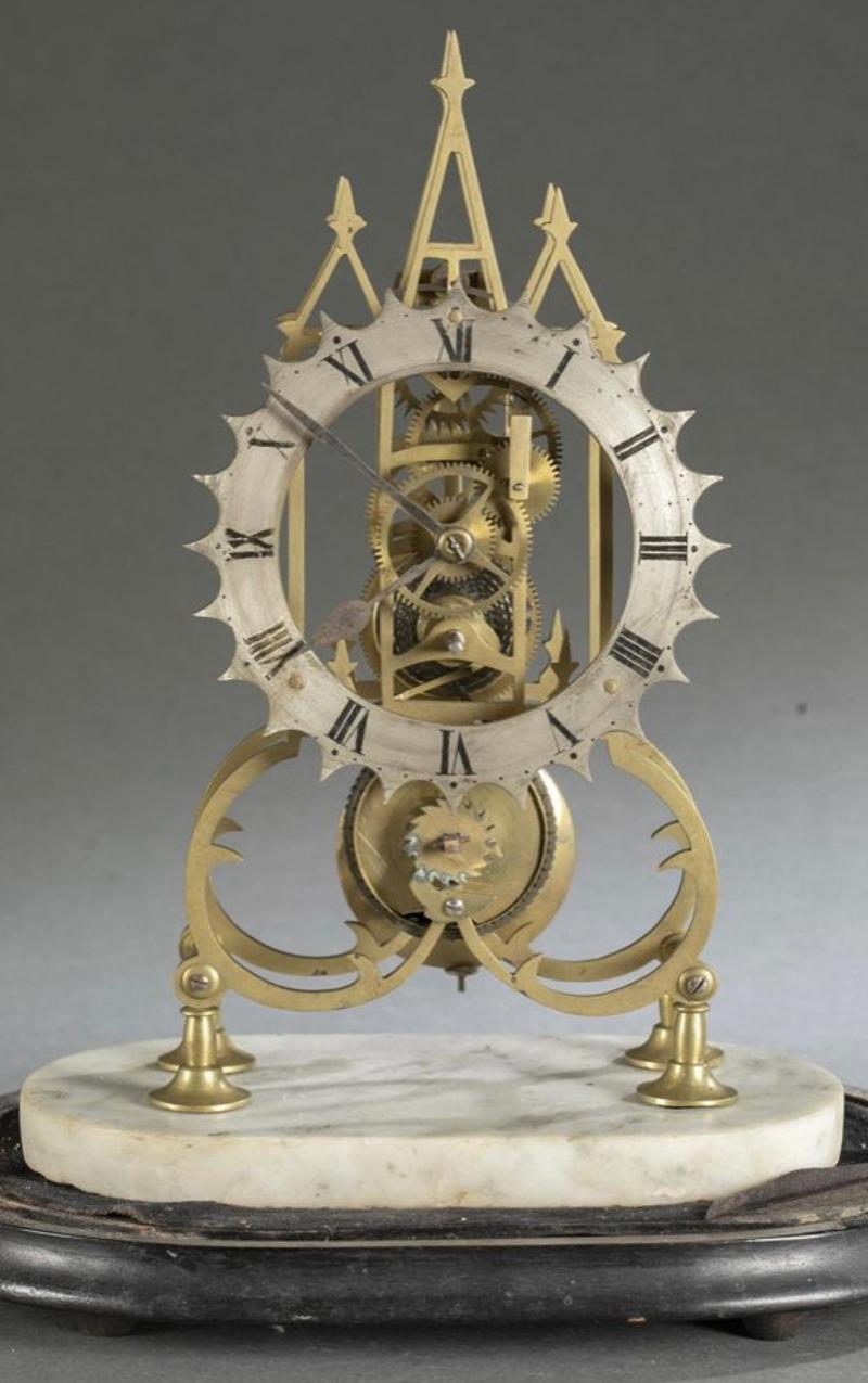 Early 19th century Gothic brass skeleton clock on marble base with glass dome. Three steeple pediment. Silvered metal face with Roman numerals. Open scroll work body on marble base. Measurements: clock - 14.5