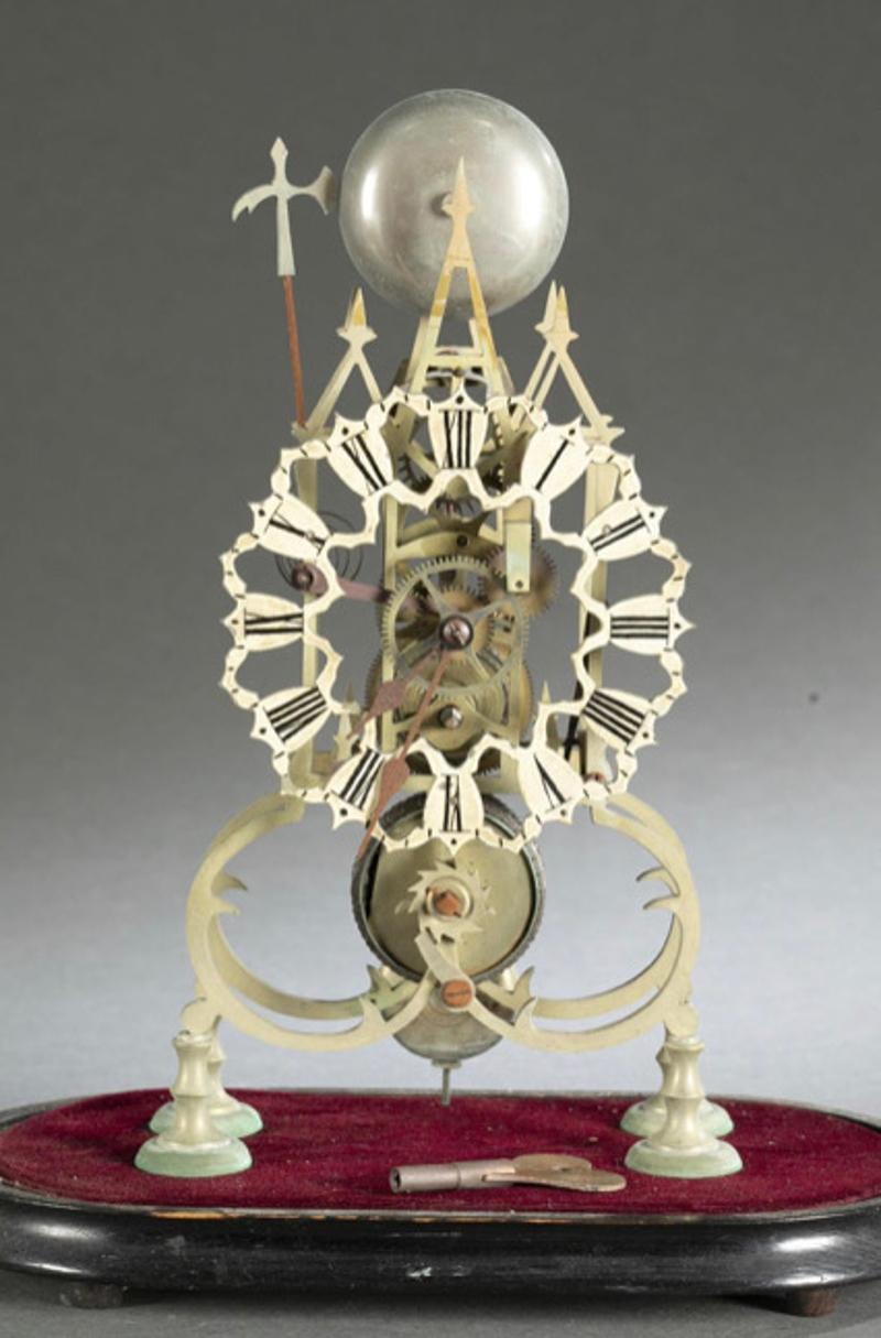 Early 19th century Gothic brass skeleton clock on wood base with glass dome. Bell on peak with steeple design and halberd hammer. Painted metal face with Roman numerals. Open scroll work body on velvet base. Measurements: clock - 15.5