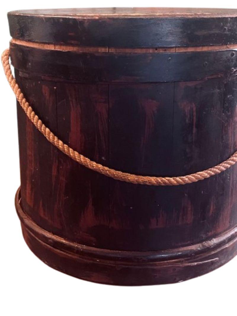 Early 19th Century Grain Painted Firkin, possibly late 18th Century, a hand crafted firkin or bucket, having a round lid above a barrel-stave built vessel held by wooden hoops, on solid wooden base, with rope handle attached through holes drilled in