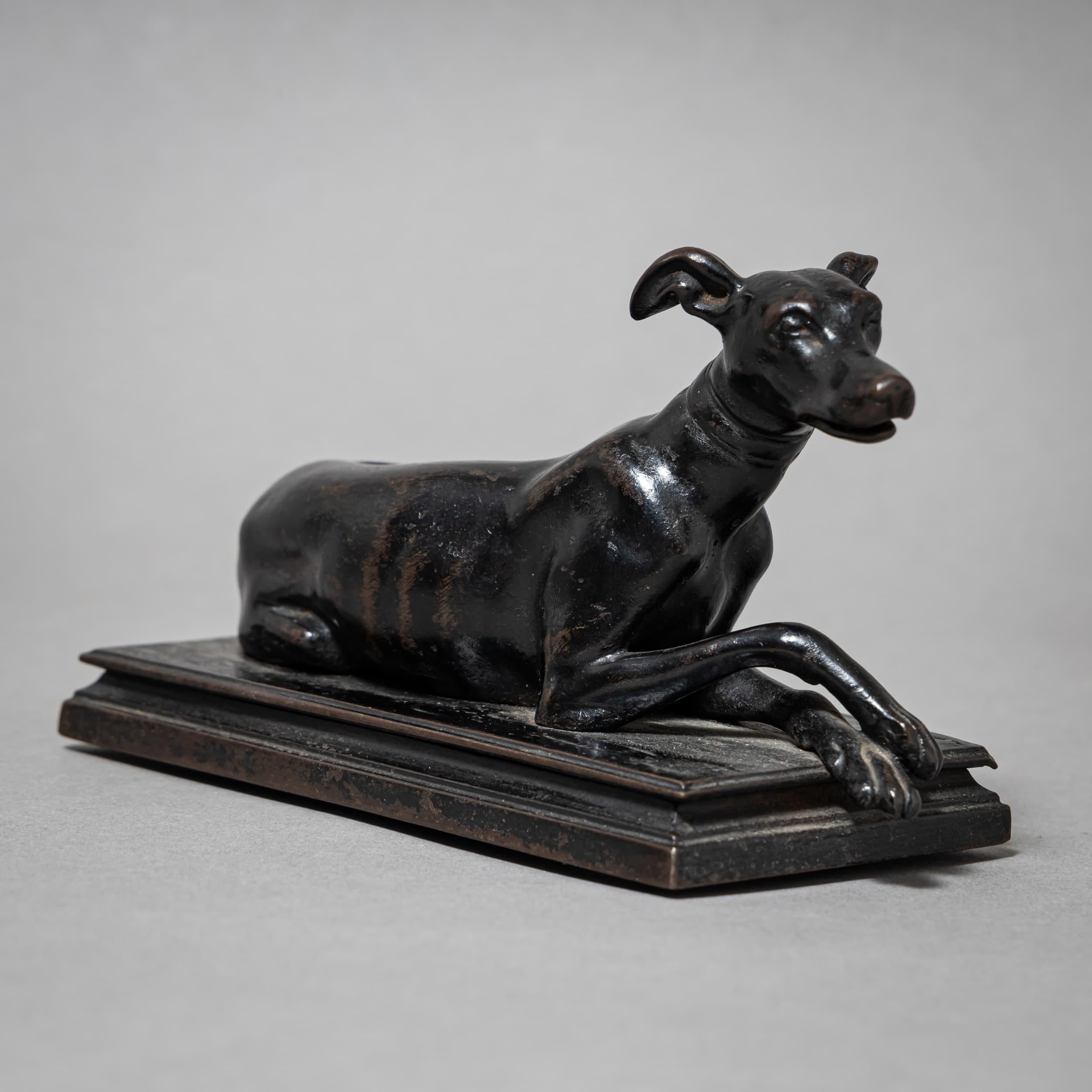 Small iron sculpture of a reclining greyhound with elegantly crossed front paws and raised head. Finely detailed, characteristic of Berlin ironwork and the delicate metal artistry of the early 19th century.