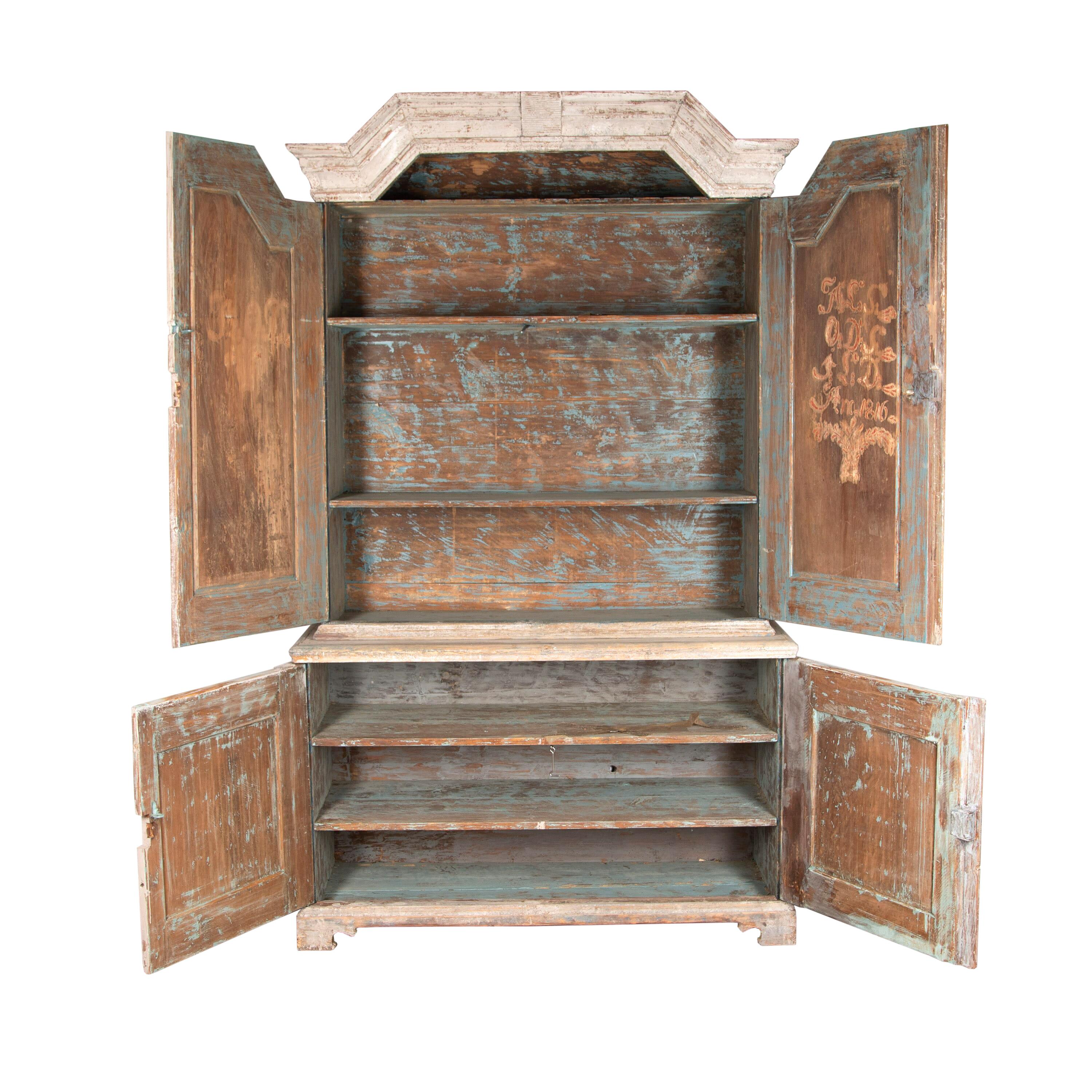 Early 19th century Gustavian cupboard with a decorative carved pediment. Featuring two doors with reeded detailing that open to useful storage. Below are two further doors with further reeded detailing to the front, opening to further storage. This