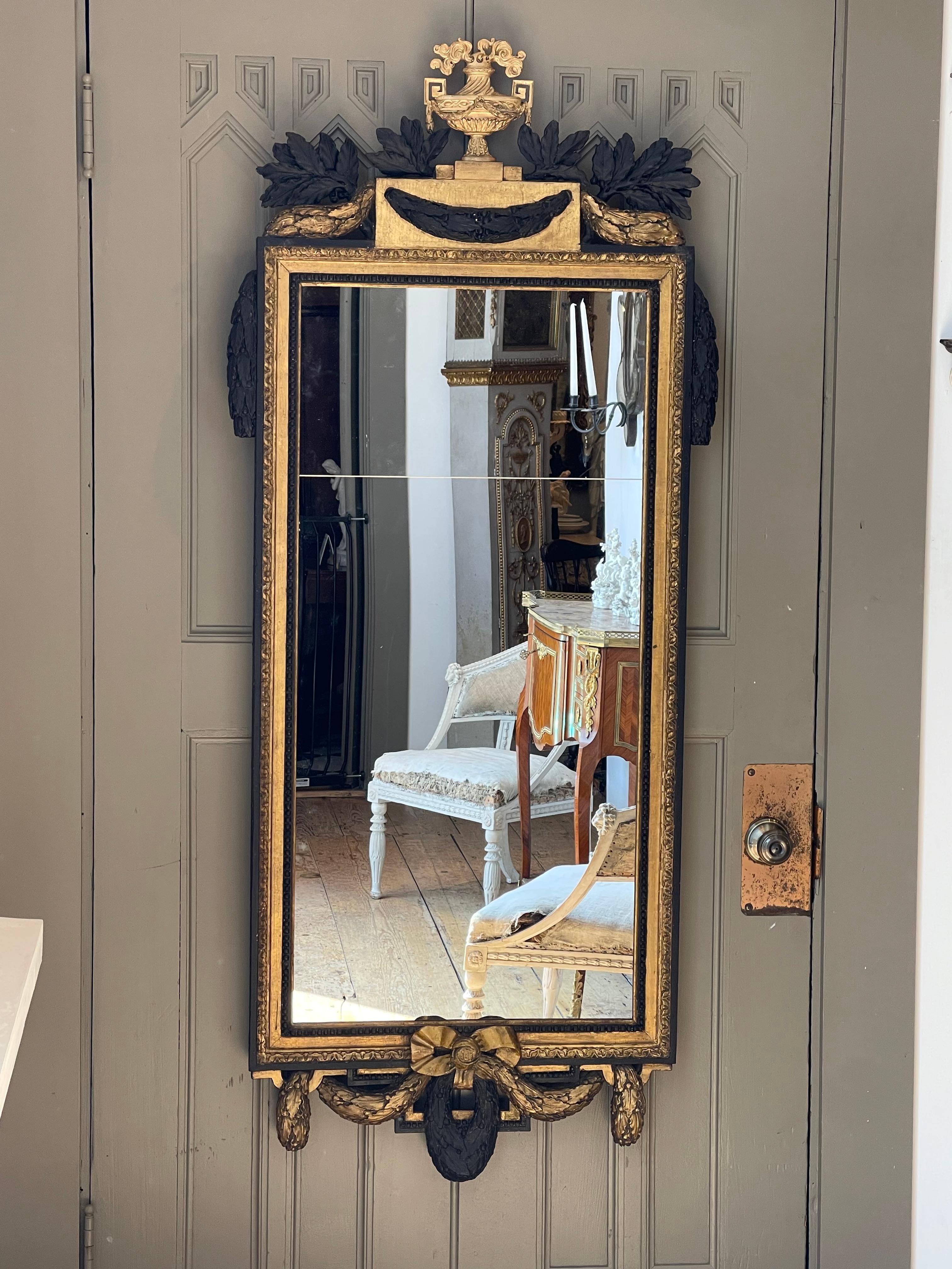 Period Early 19th Century Giltwood Gustavian Mirror.  Urn top with swags of painted laurel.  Original gilding.  Laurel tied with bow at bottom.  Replaced mirror.  