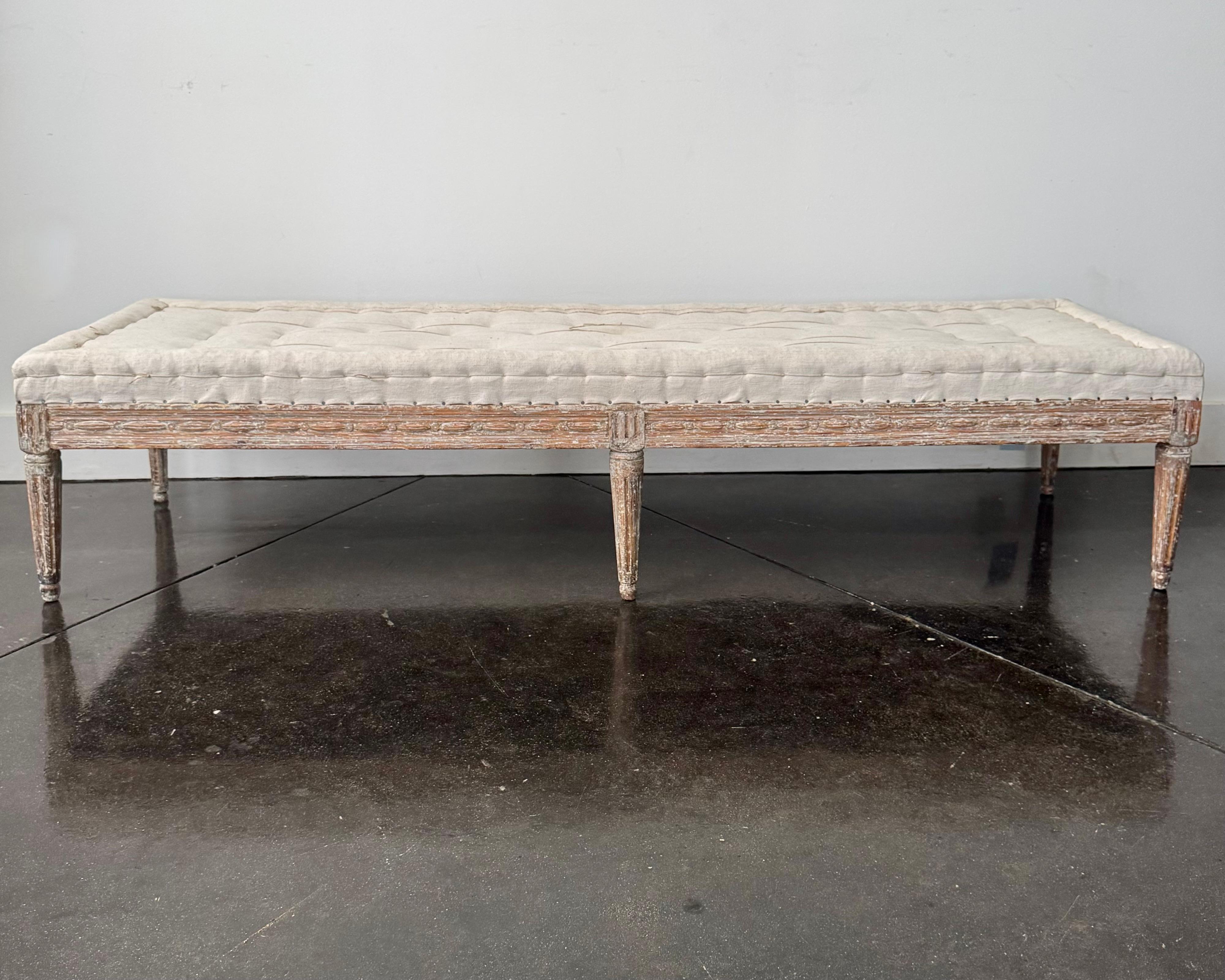 Très rare. Banc suédois d'époque gustavienne, vers 1800, fini sur les trois faces  Les côtés sont ornés de sculptures en guilloché et reposent sur des pieds cannelés ronds. La finition d'origine crème/blanc a été grattée et tapissée de façon