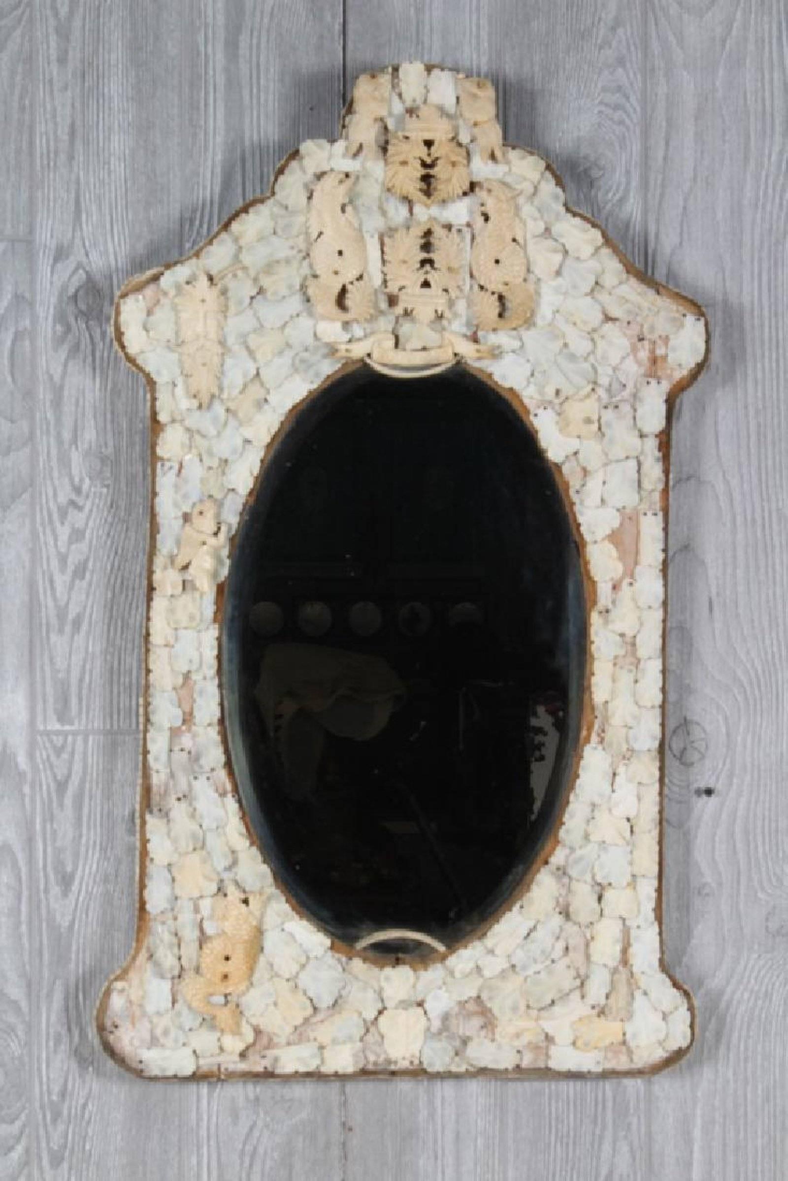 Rare early 19th century hand carved European Dieppe bone mirror with carved shield forms, armorials and cherubs with an aged bevelled mirror plate. Wear consistent with use and age.

  