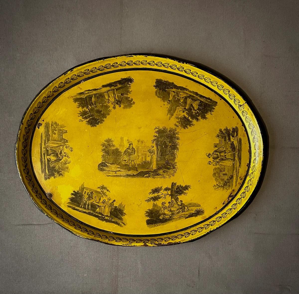Ce vibrant plateau à toiles français du début du XIXe siècle, inondé d'une teinte jaune ensoleillée, présente de charmants motifs de toile qui dépeignent des scènes idylliques de la campagne française. Réalisée en fer blanc émaillé, cette pièce