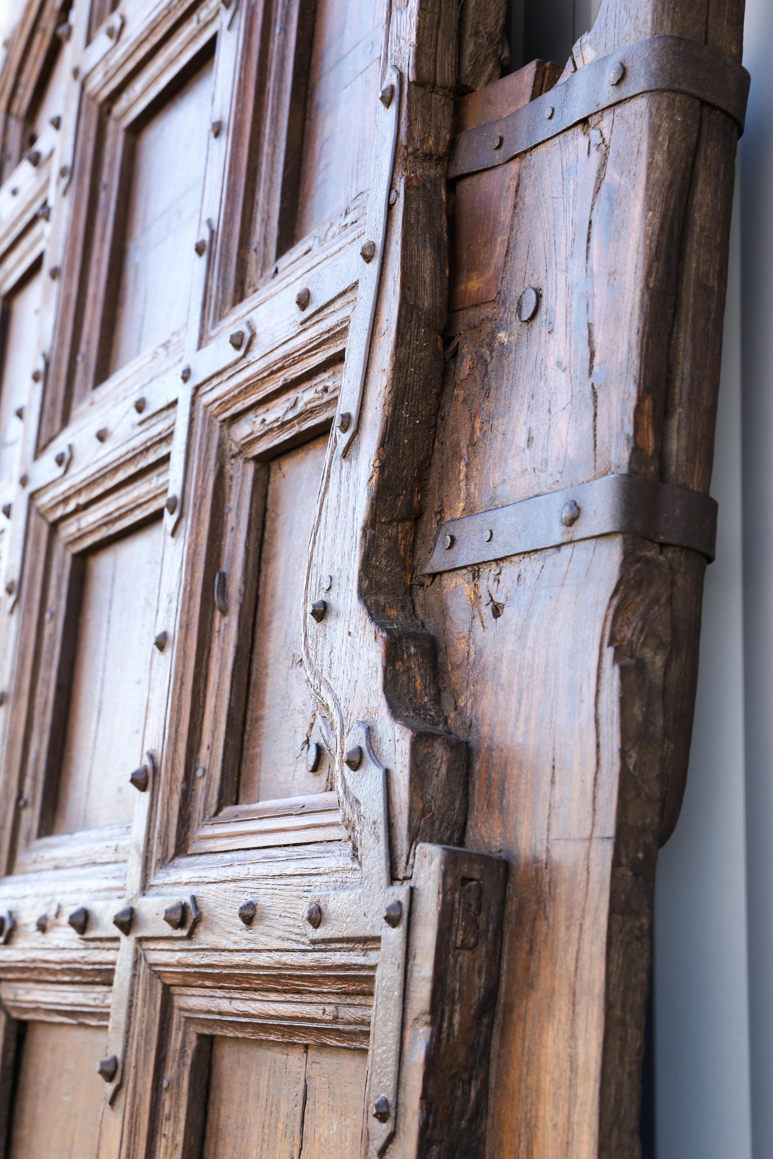 This is a large solid teak wood heavily made doors used in castles. The age of these doors can be determined by the general construction and also by the way the doors are attached to the building. The two pegs on the doors revolve on the toughs