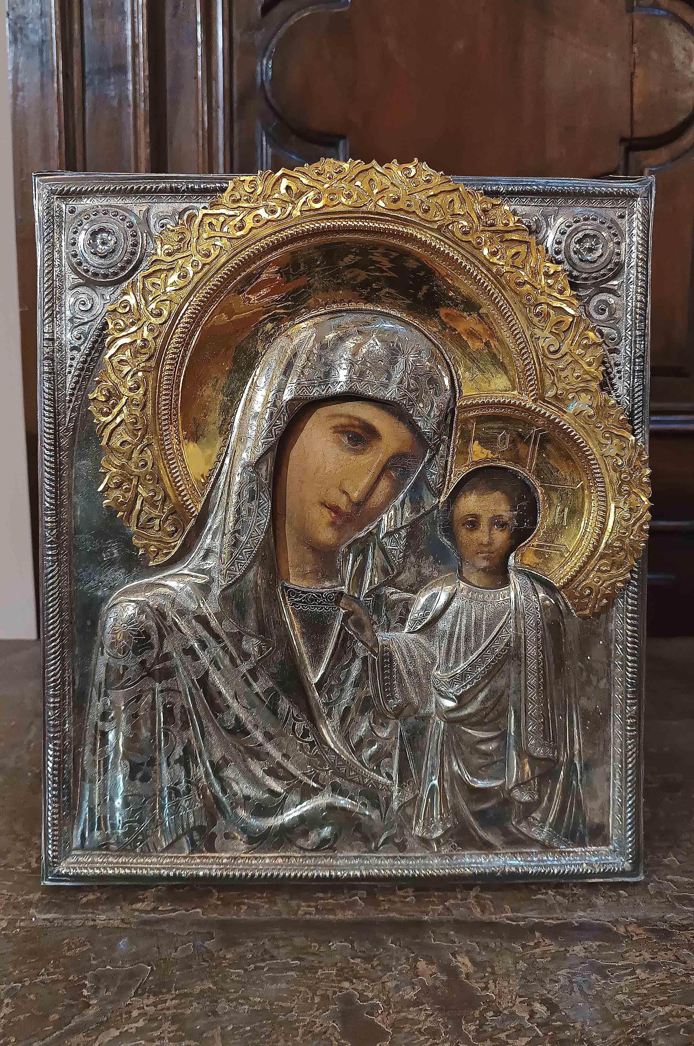 Beautiful icon painted in oil on a tablet with a silver frame and gilded silver haloes. The representation of the Madonna and child is frontal, with intense and expressive gazes. Their clothes are richly decorated in silver, engraved creating