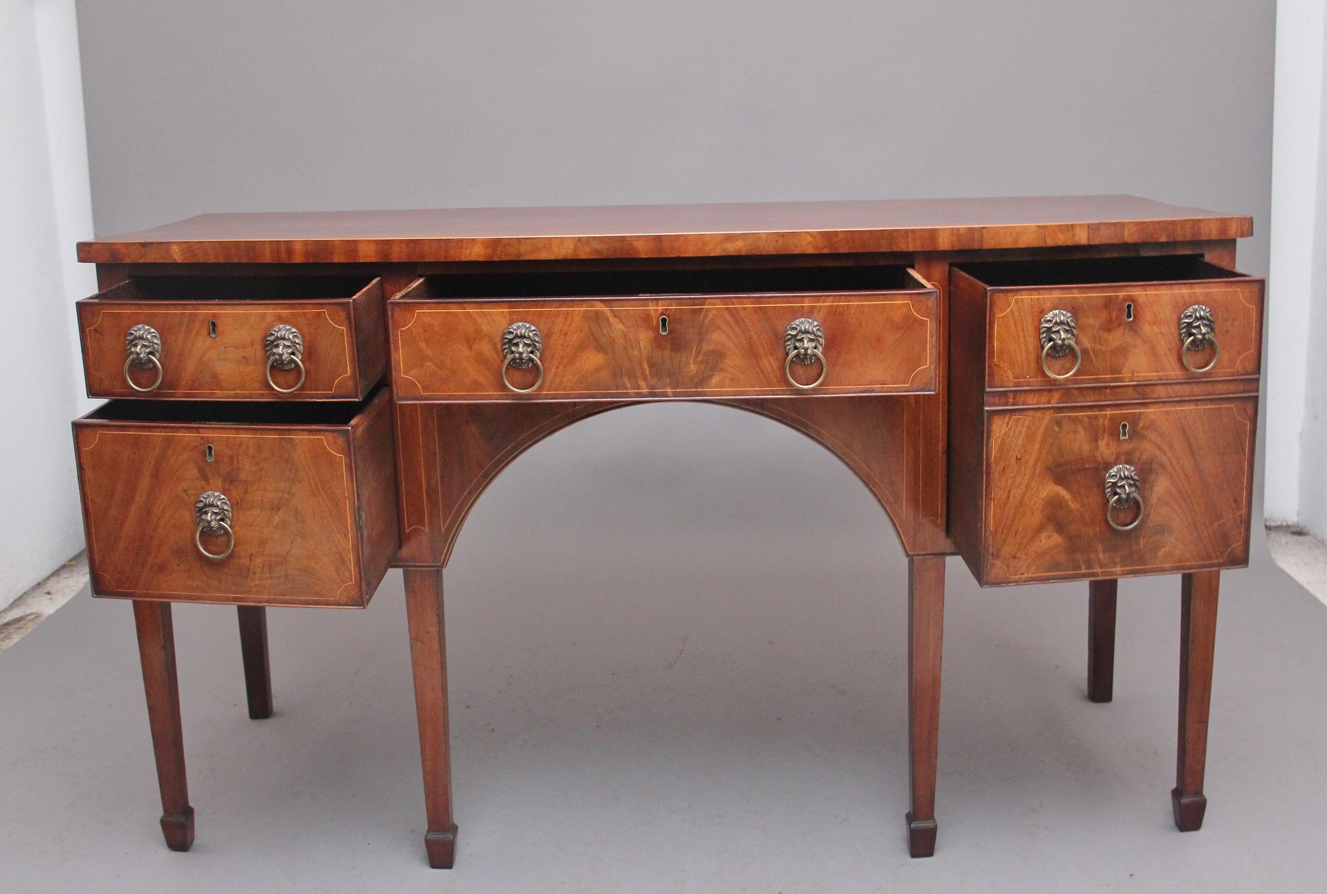 Early 19th Century inlaid mahogany sideboard, having a lovely figured shaped top, the front of the sideboard looking like it has a combination of five drawers but in fact it has a large deep drawer to the right, the drawer fronts have decorative
