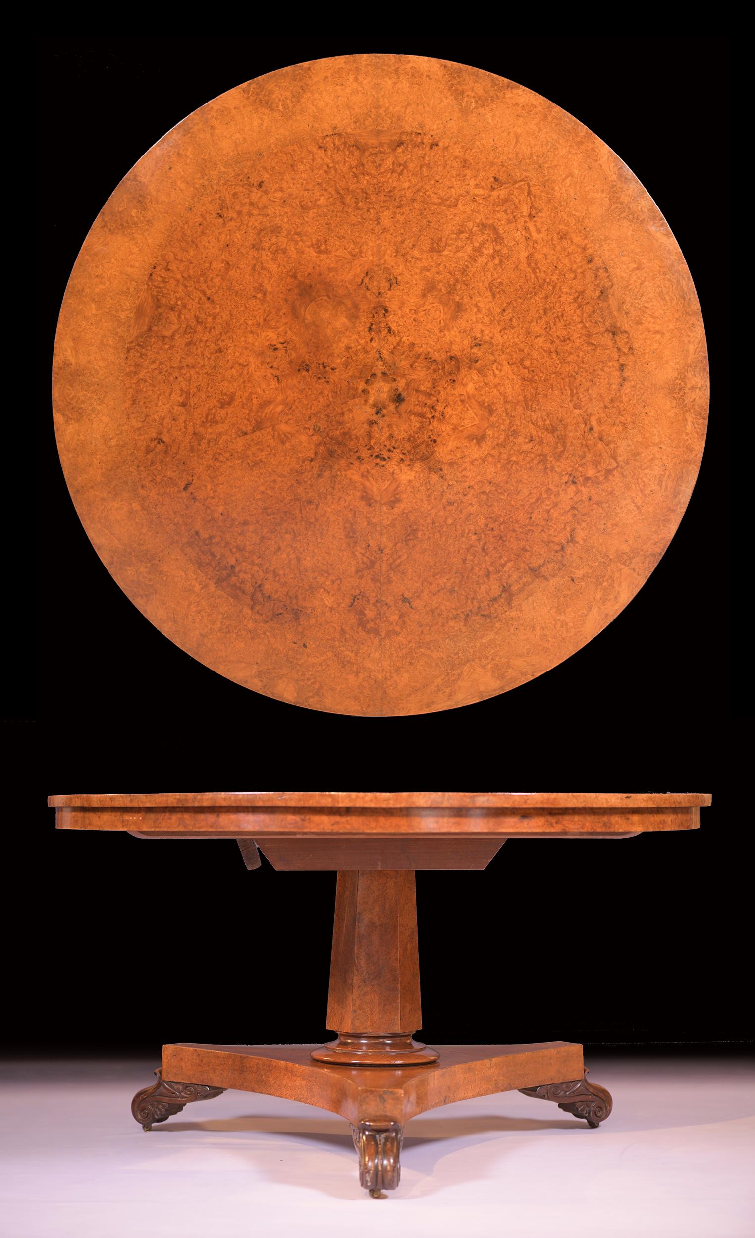 The circular top veneered in extremely well figured amboyna having a cross banded outer border. The top supported on a octagonal column, similarly veneered in amboyna, resting on a tripartite platform base with scroll carved feet. Stamped and No.
