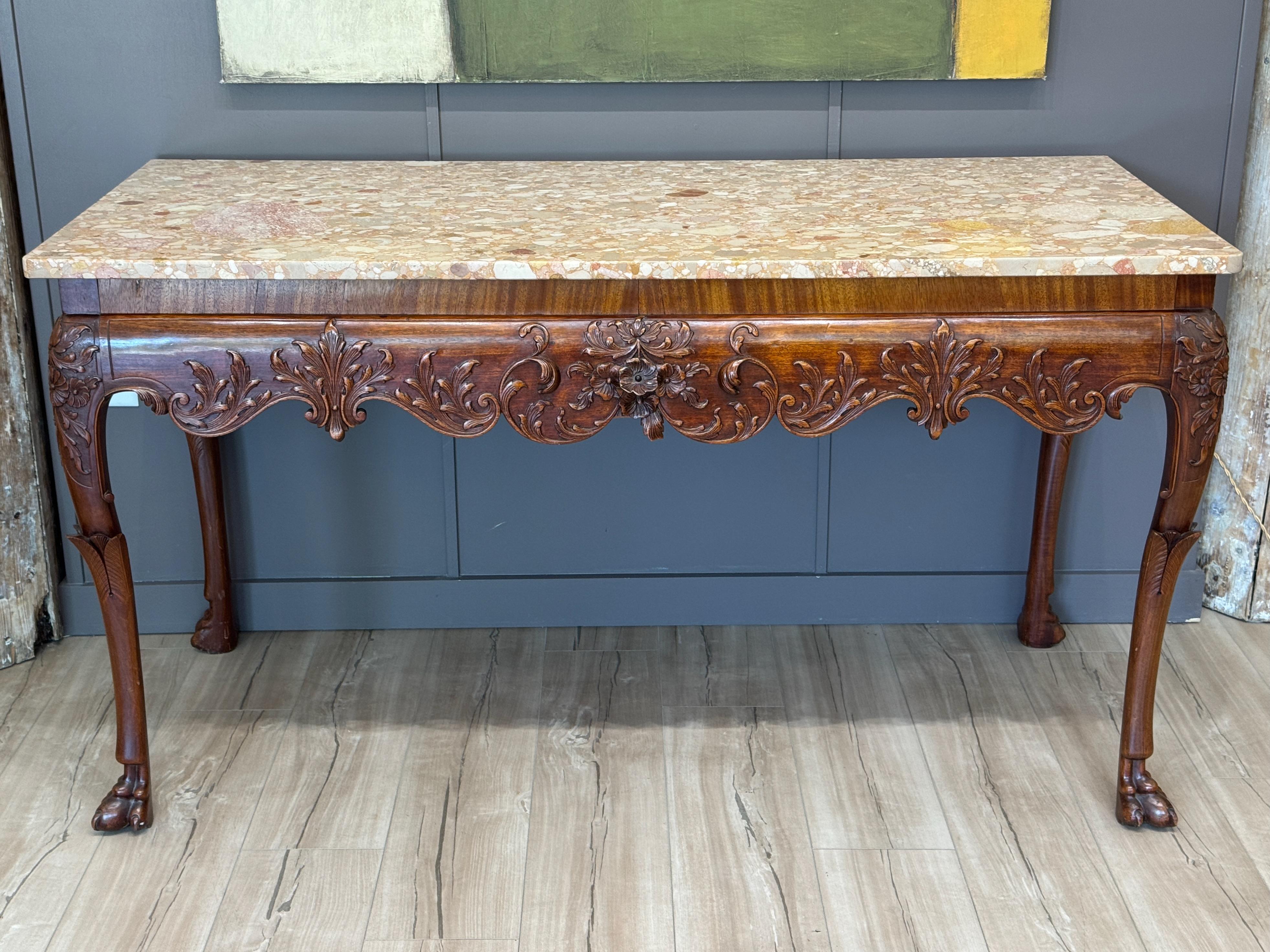 A finely carved Irish console table from the early 19th century with richly detailed apron and cabriole legs ending in paw feet. The shaped frieze is adorned with acanthus and scrollwork, all supporting a beautifully figured marble top. Close-up