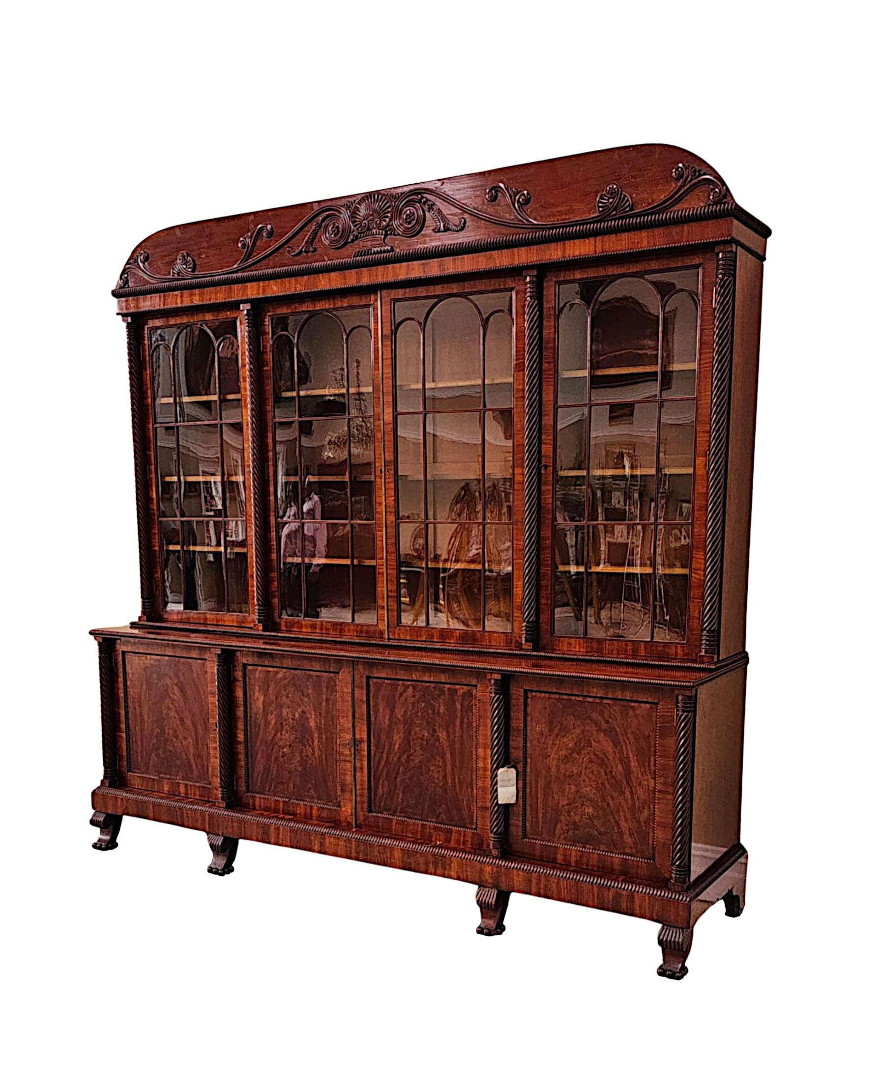 Una rarissima e raffinata libreria a quattro ante in mogano a fiamma irlandese dell'inizio del XIX secolo, di qualità eccezionale, splendidamente intagliata a mano con una patinatura e una venatura molto ricche.  La corona, sagomata e ricurva, è