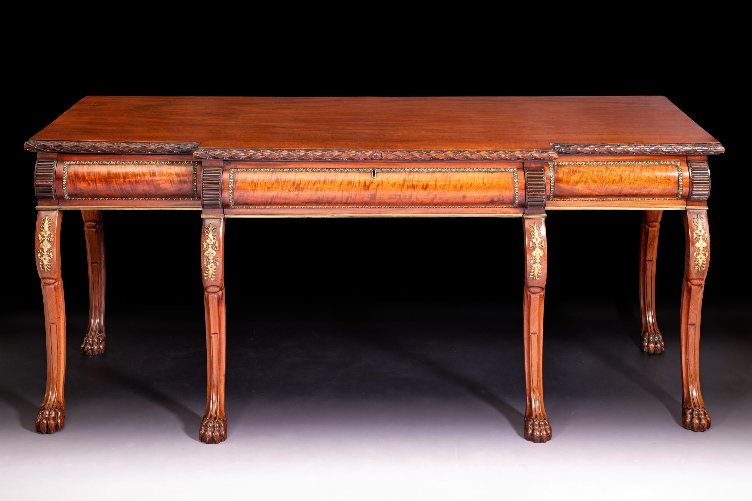 A very fine Regency mahogany console table, the breakfront top with laurel leaf carved rim, above three frieze brass mounted drawers, raised on six elegant cabriole legs, the scroll supports are adorned with fine ormolu mounted decoration,