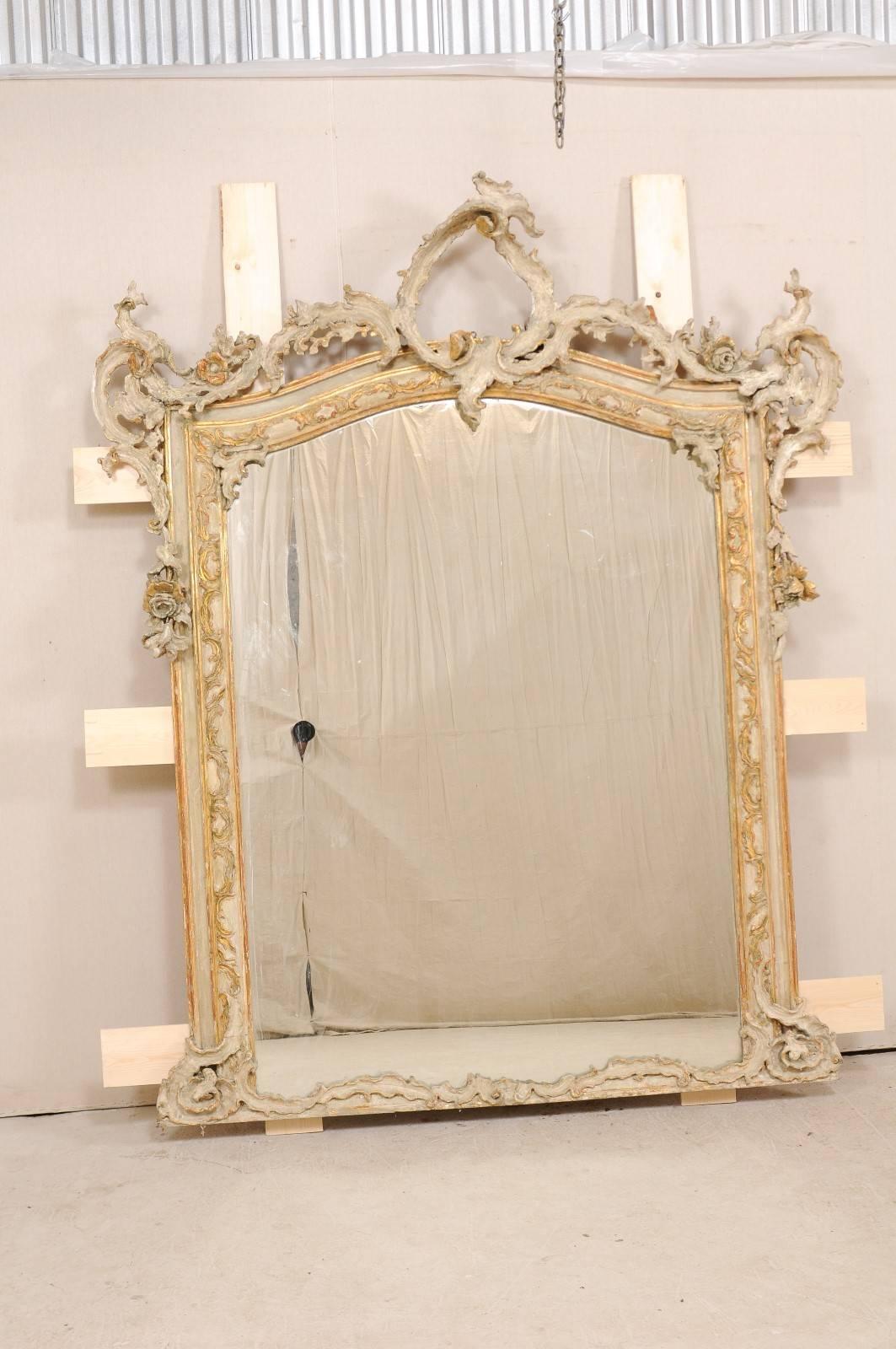 A magnificent Italian Baroque style mirror from the early 19th century. This antique Italian mirror is grand in scale, standing at approximately 7.5 feet tall, and over 6 feet wide. Finely hand-carved Baroque style detailing, in a rich foliage