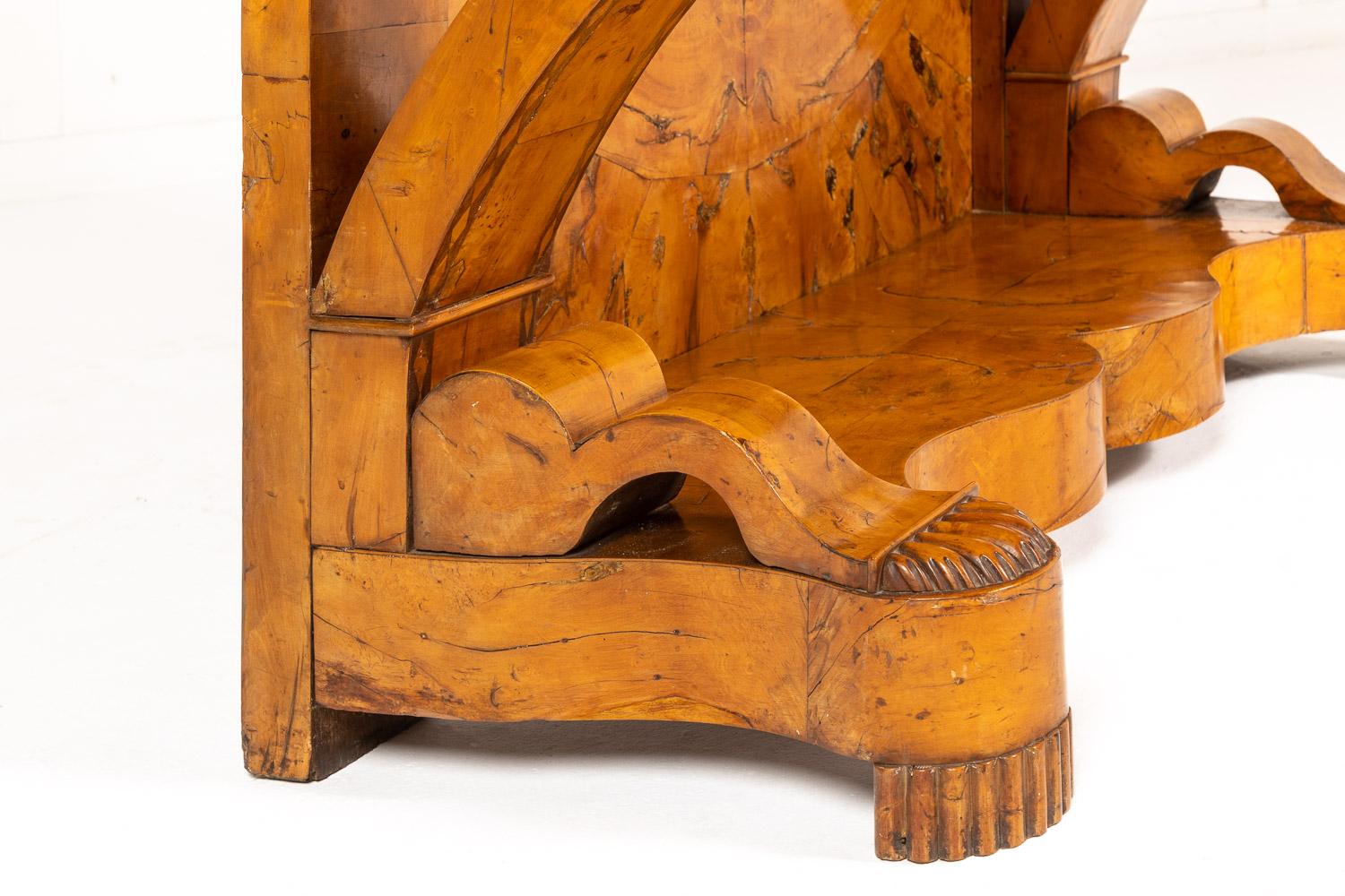 Table console italienne du début du XIXe siècle, en ronce de bois et noyer. Il présente un plateau rectangulaire étagé et mouluré au-dessus d'un tiroir en frise dissimulé. Soutenu par d'épaisses et élégantes extrémités en volute avec une