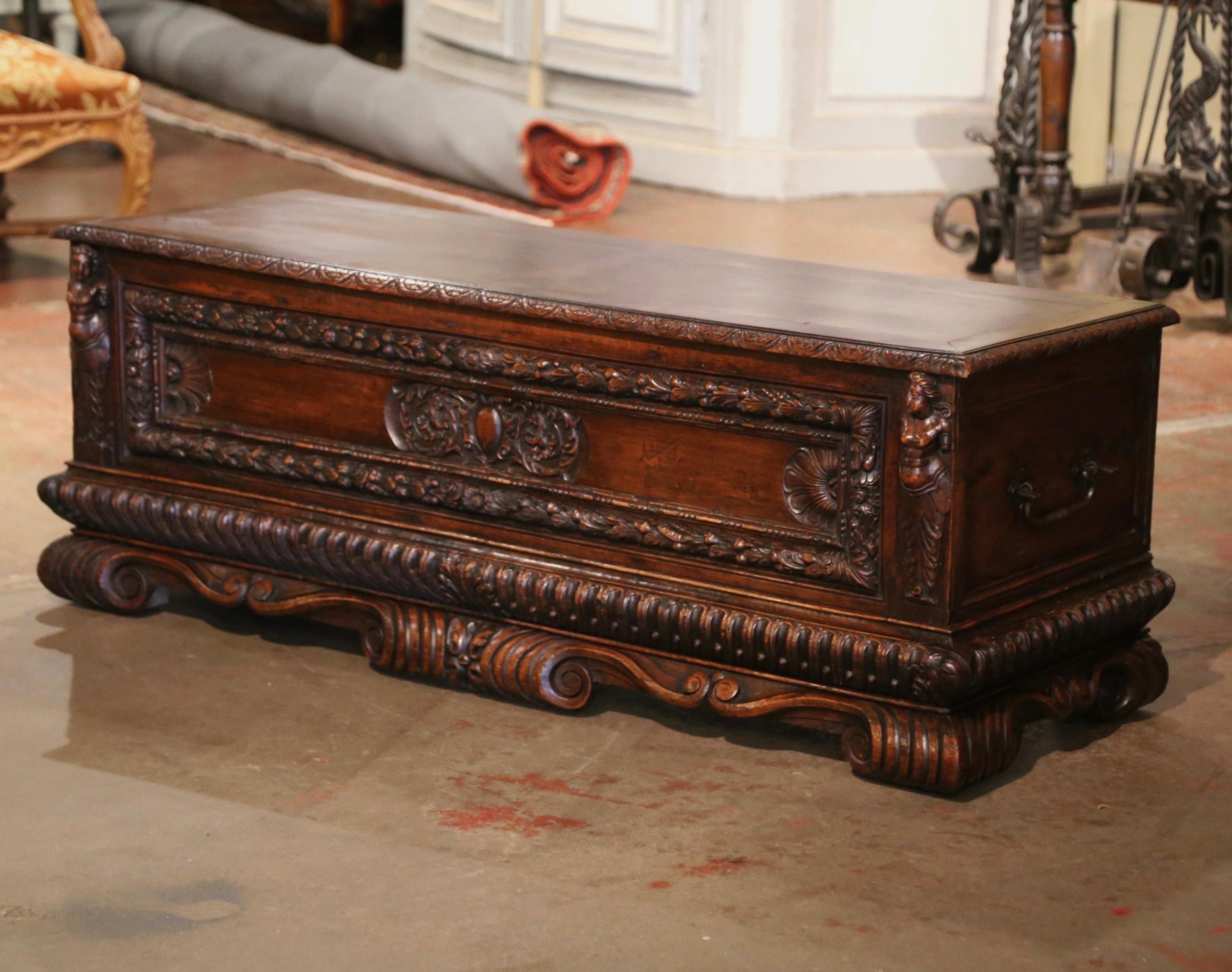 This elegant, antique fruitwood cassone was crafted in Italy, circa 1830. Standing on five scrolled feet over a scalloped apron, the base of the stately trunk is decorated with a figure on either side, and the facade panel features a foliage gilt