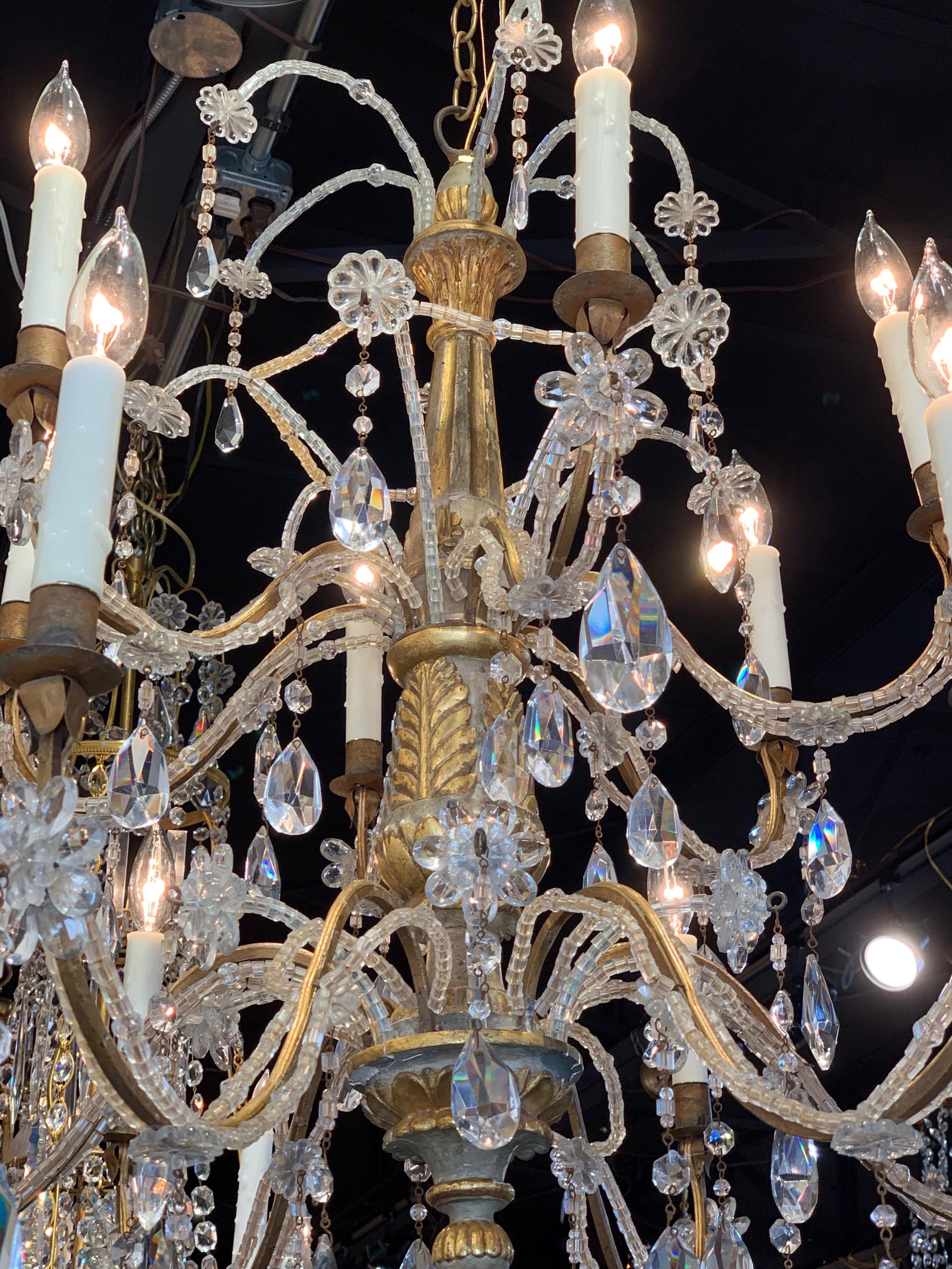 Gorgeous 19th century carved wood and beaded chandelier with 12 lights. There are 2 tiers on the fixture and it is decorated with beads, flowers and prisms. Also, very beautiful gold gilt on the carved wood.