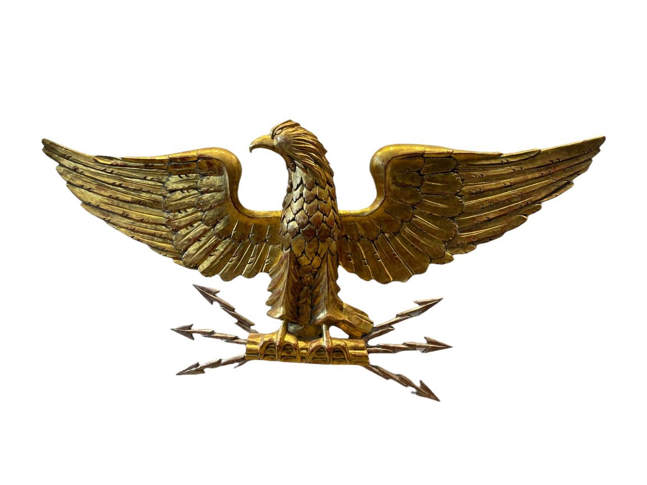 Early 19th century Italian carved wood gold gilded Eagle. Its wings spread and clutching a set of white gold gilded lightning bolt arrows in its talons.
 