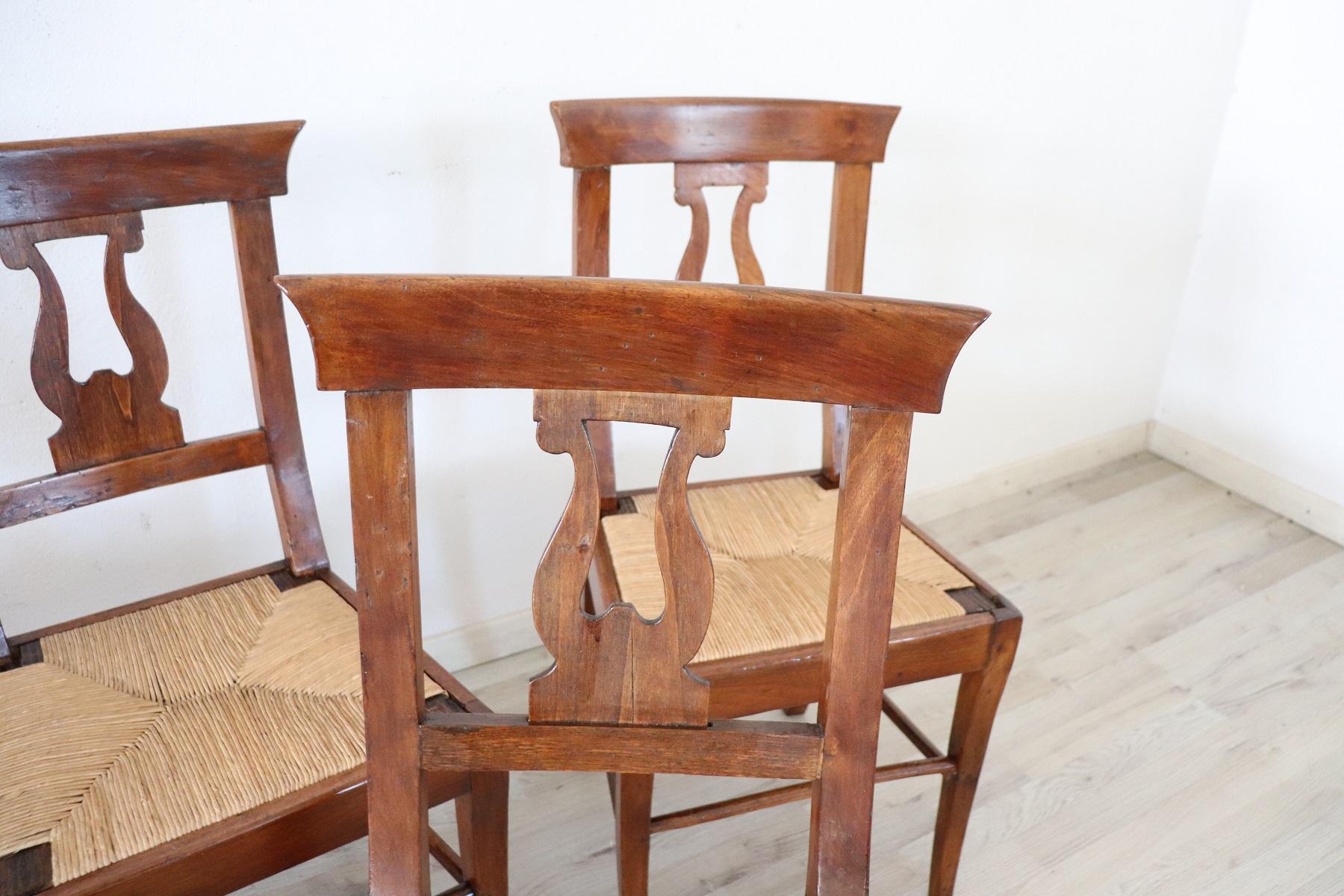 Series of four refined early 19th century authentic Italian Empire walnut wood four chairs. Refined decoration the back is carved in the shape of a lyre. The legs are very elegant straight. The seat is wide and comfortable rustic in handwoven straw