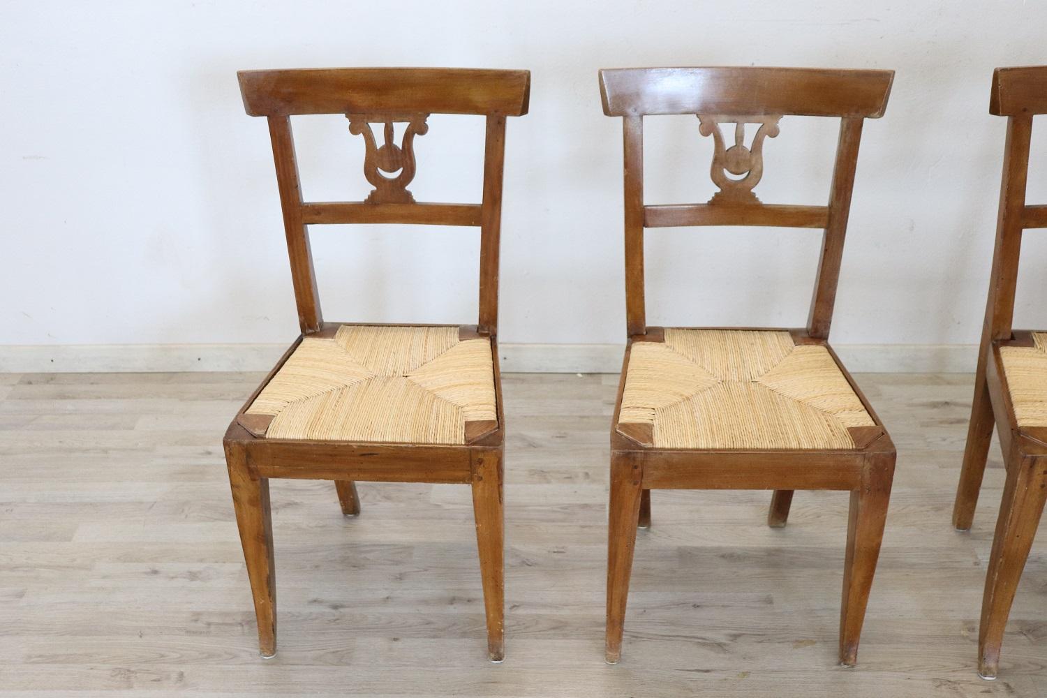 Série de quatre chaises raffinées en bois de noyer Empire italien authentique du début du XIXe siècle. Décoration raffinée : le dos est sculpté en forme de lyre. Les jambes sont très élégantes et droites. Le siège est large et confortable rustique