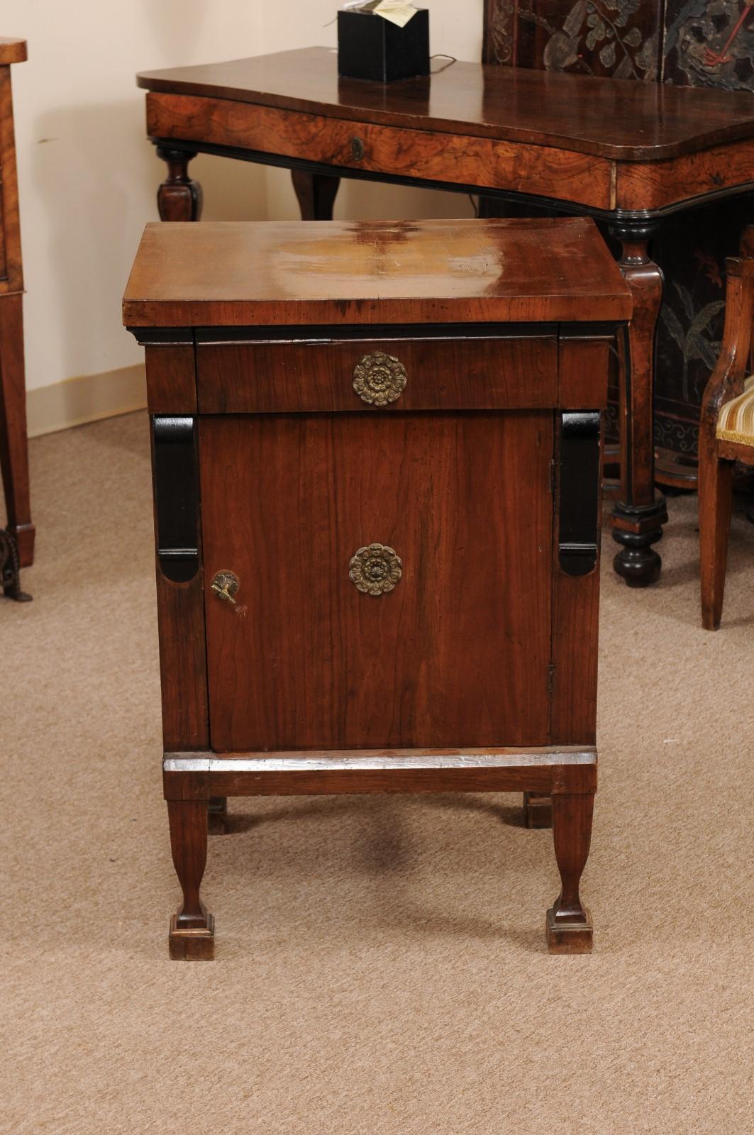 The early 19th century Italian Empire commodino with ebonized detail, 1 drawer above cabinet below and gilt metal mounts. All resting on raised shaped legs.