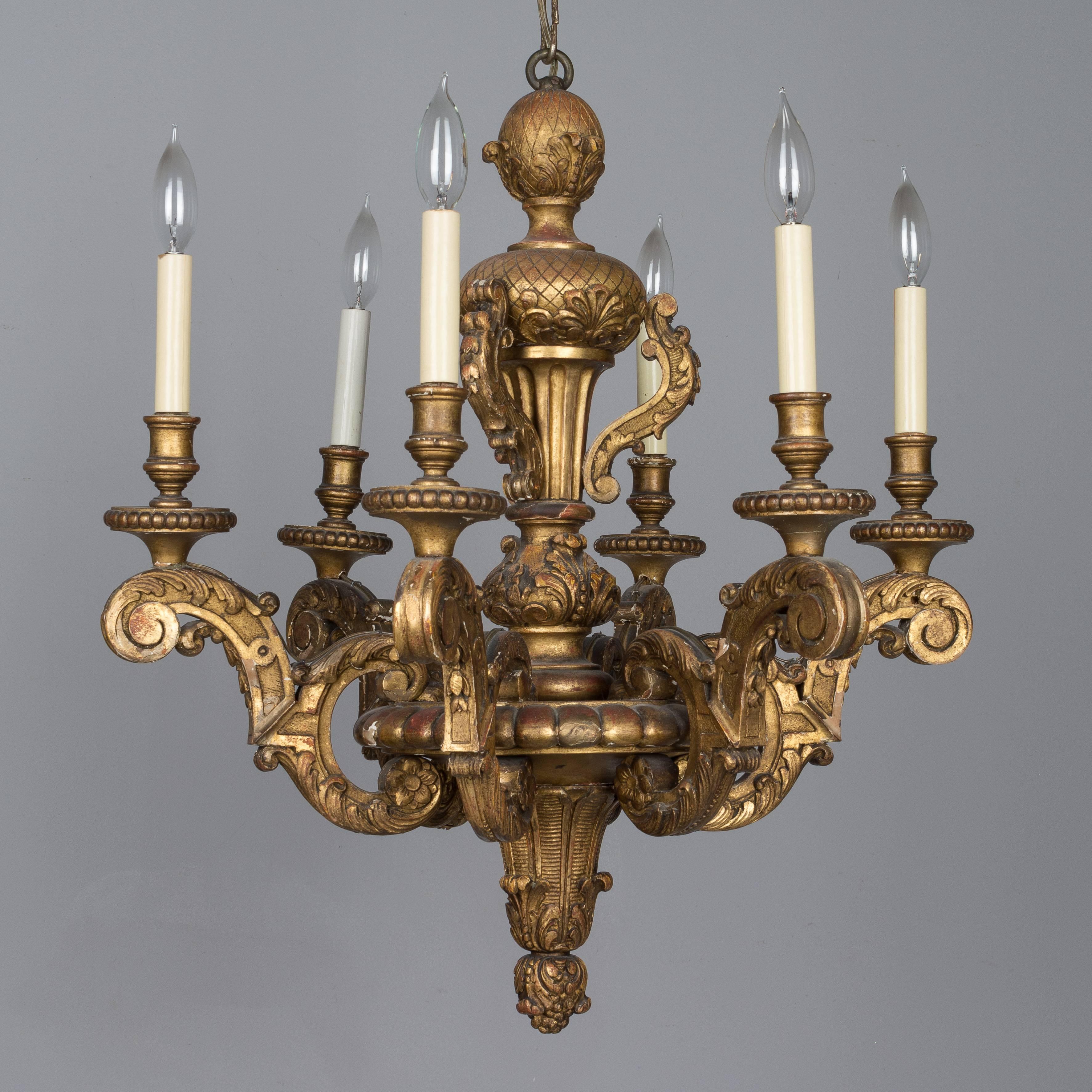 An early 20th century Italian giltwood six-light chandelier with boldly carved Baroque form. There are some losses to the gilt and it has been touched up in places. In overall good condition. Wired with new sockets and candle covers. Please refer to