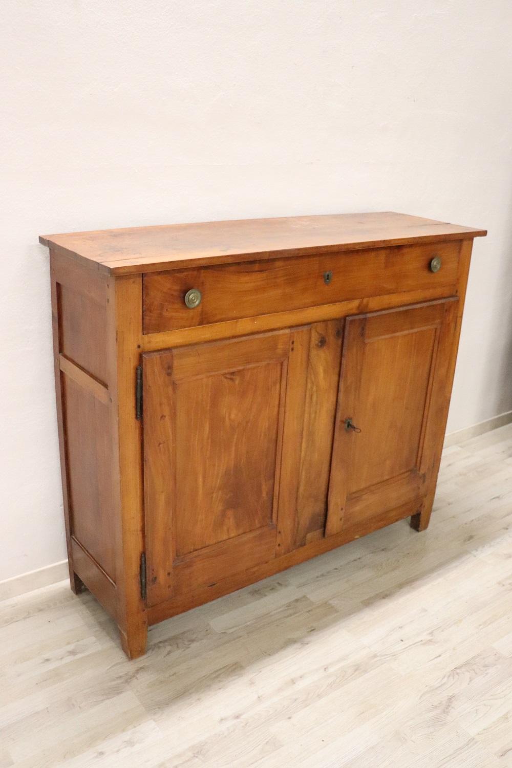 Beautiful antique sideboard in solid cherry wood made in 1810s. The line is simple and essential in Louis XVI Style, perfect to be placed also in a modern environment. Beautiful patina of cherry wood. Ample useful internal space equipped with one