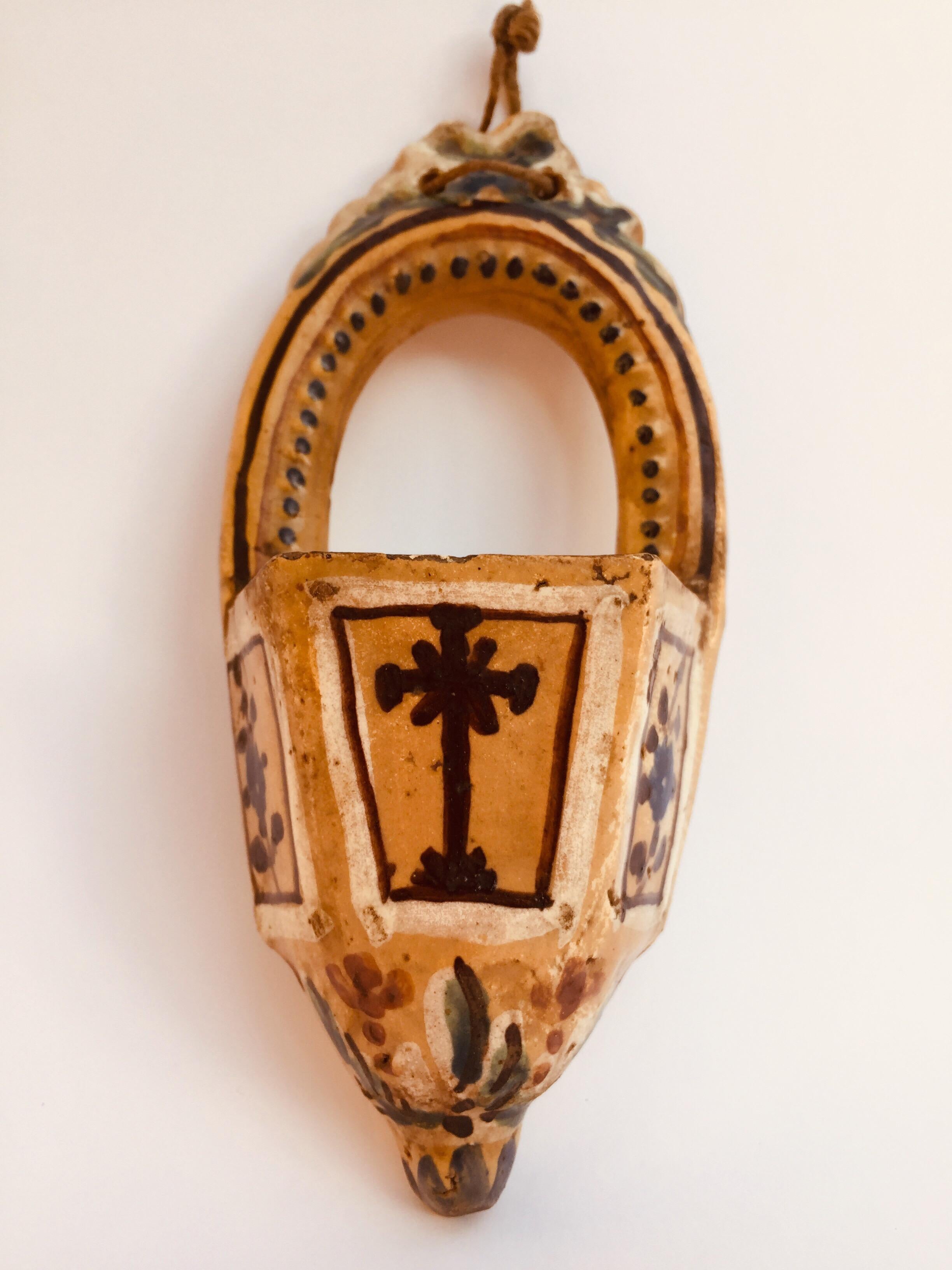 Small and lovely Italian  Holy Water font from Italy, a shaped polychrome ceramic artwork dating back to Neoclassical period, early 19th century. 
This rare religious work is finely hand painted with ocher green and beige motifs on the font, a