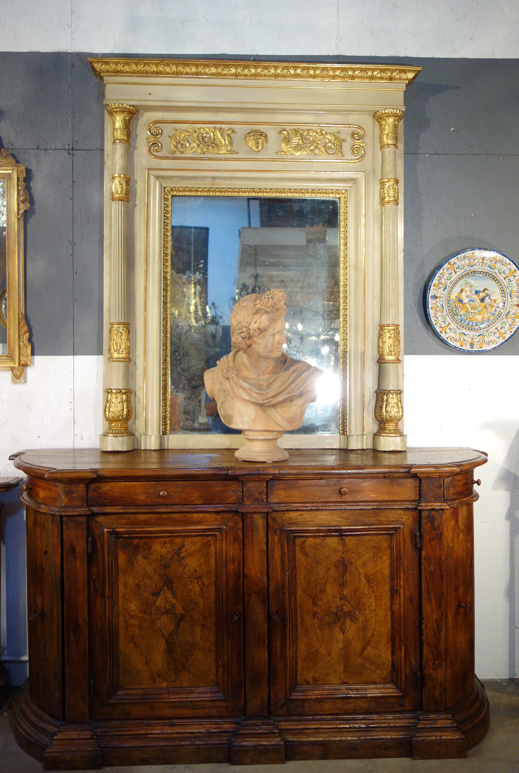 Grand miroir Trumeau italien de style néoclassique, finement orné. La laque beige patinée, vieillie par le temps, s'associe aux détails en bois doré pour créer une architecture grandiose et impressionnante. La période néoclassique s'est inspirée des