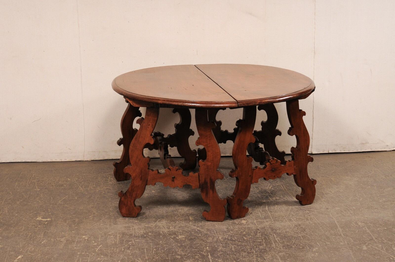 An Italian pair of beautifully-carved, lyre leg console tables from the early 19th century. These antique tables from Italy each feature a half-round/demi-style tops, which are raised upon a pair of sinuously carved and slightly canted lyre-legs