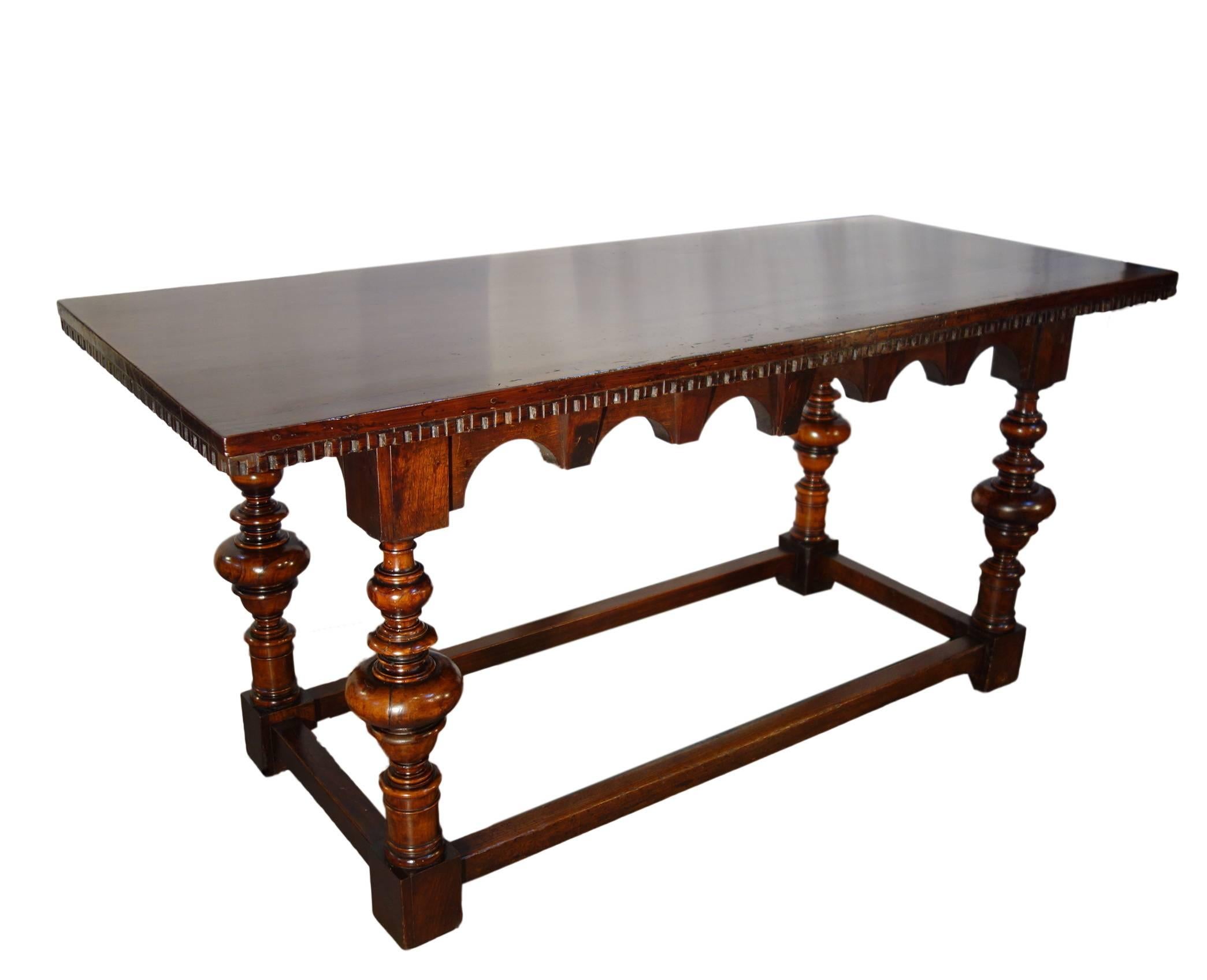 Finely handcrafted solid Italian walnut table of the Bologna style and origin with dentil edge, interesting architectural shaped apron, spool legs and straight stretchers. Nice scale and balance of contrasting forms. Well-preserved, rich patina,