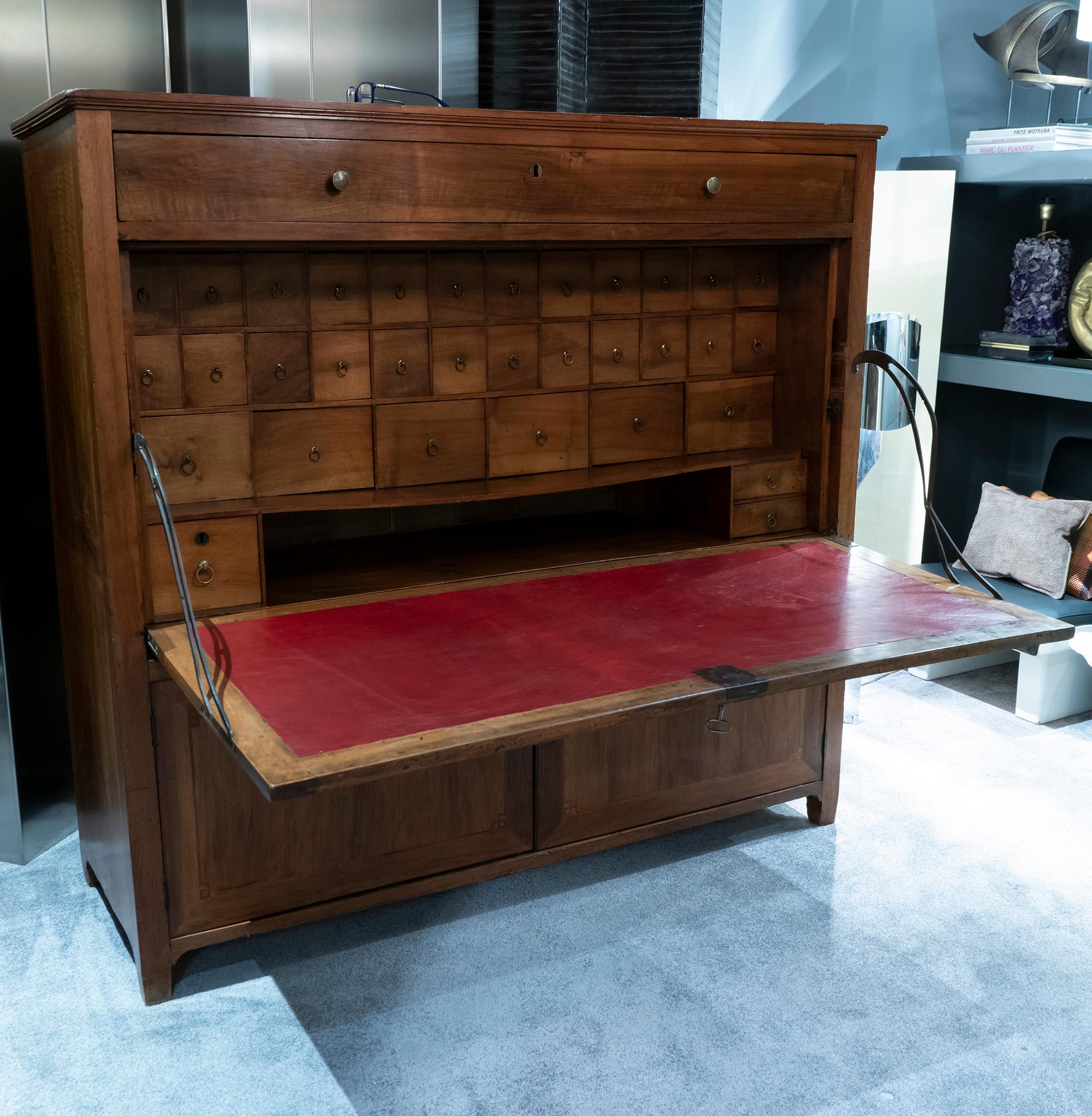 Italian walnut secretaire, above a big drawer and fall front which open to reveal original fitted interior with drawers and replaced red leather writing surface, lower section with doors and fixed shelf, all original metal elements, all with perfect