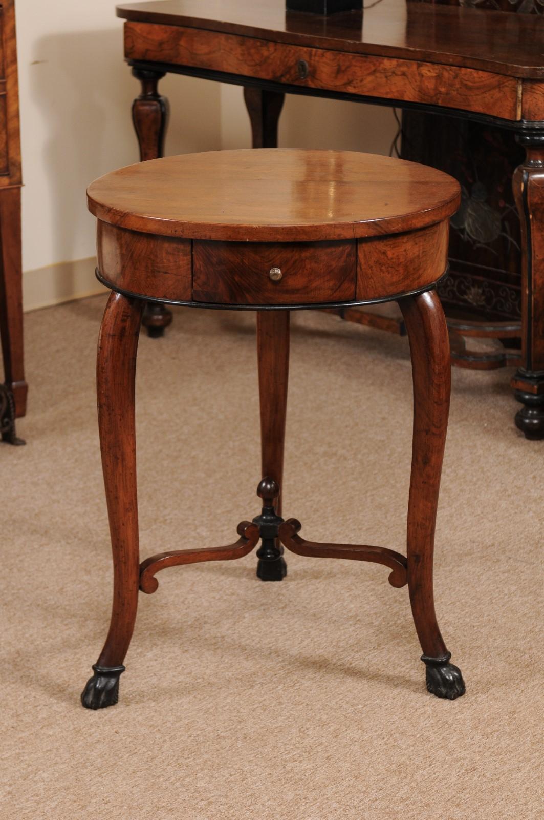 The early 19th century Italian walnut gueridon with ebonized detail, cross-stretcher and carved paw feet.