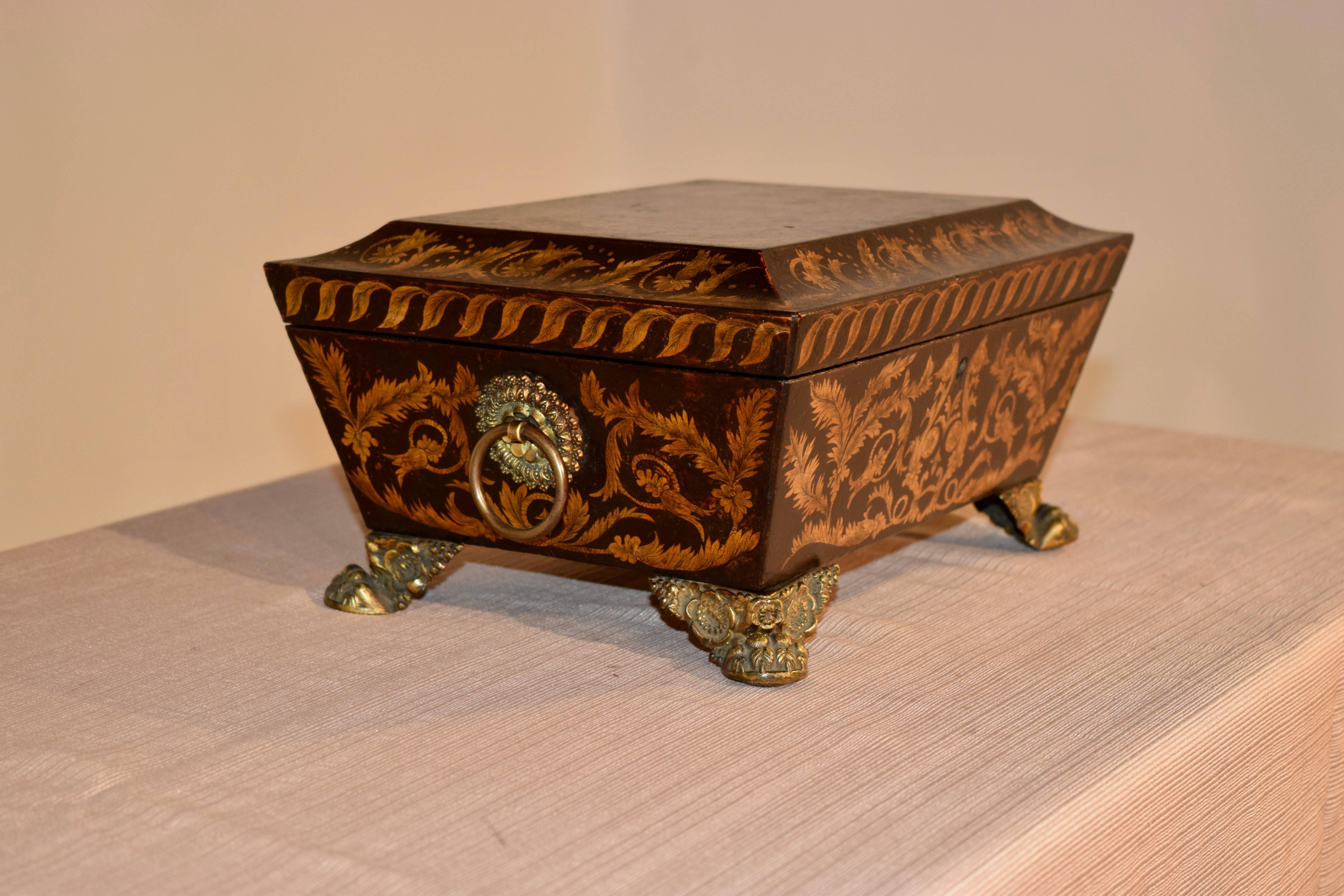 Early 19th century dresser box made of leather with hand stenciled decoration. The sides have applied pulls, which are wonderfully hand casted brass. The feet appear to be original and are hand cast brass paws with floral decoration. The box opens