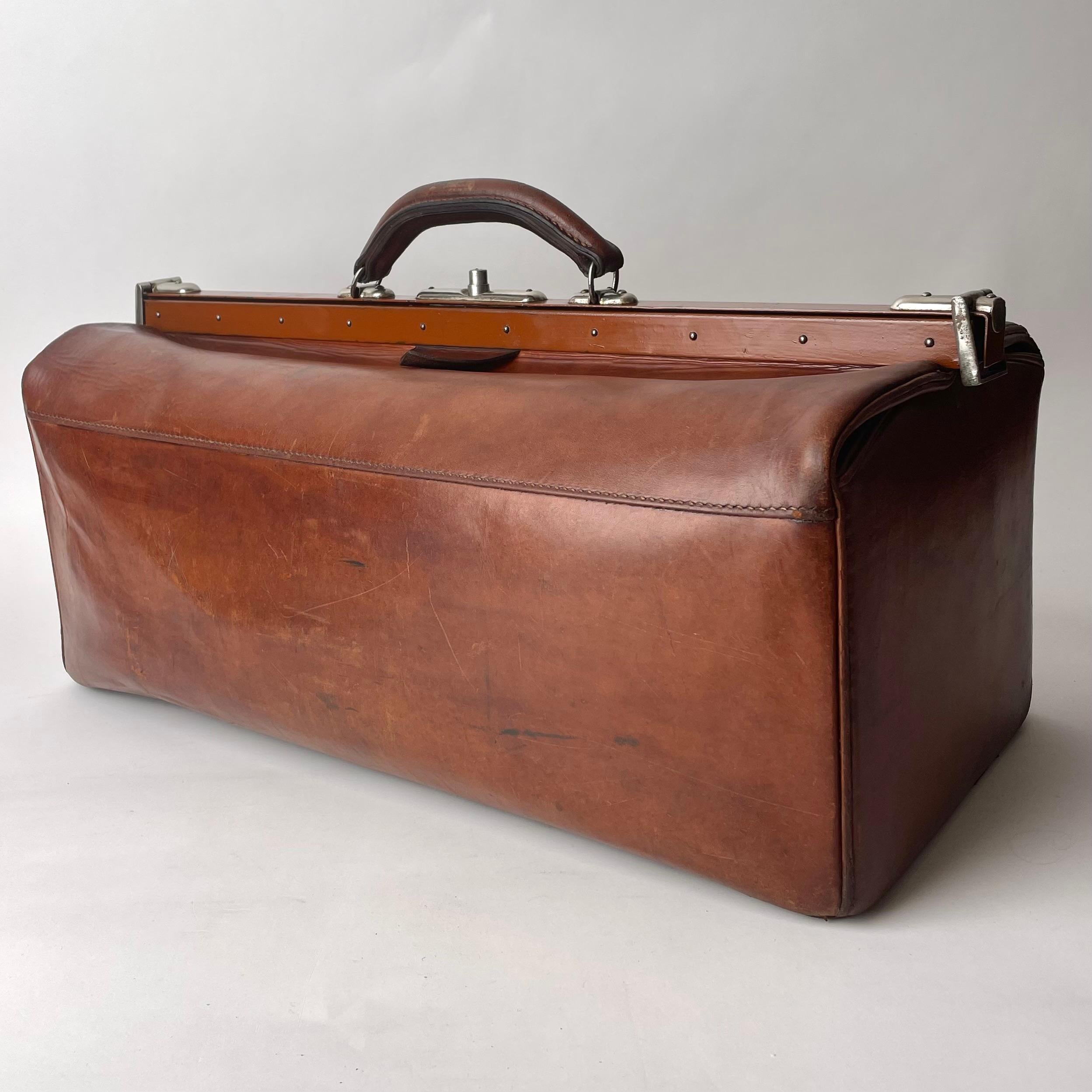 A Vintage Luggage Travel Bag in Brown Leather with Nickel Details. Early 19th Century Europe. 

A sleek and elegant vintage luggage bag in beautiful brown leather. Complete with nickel details and a functional lock mechanism. 

Wear consistent with