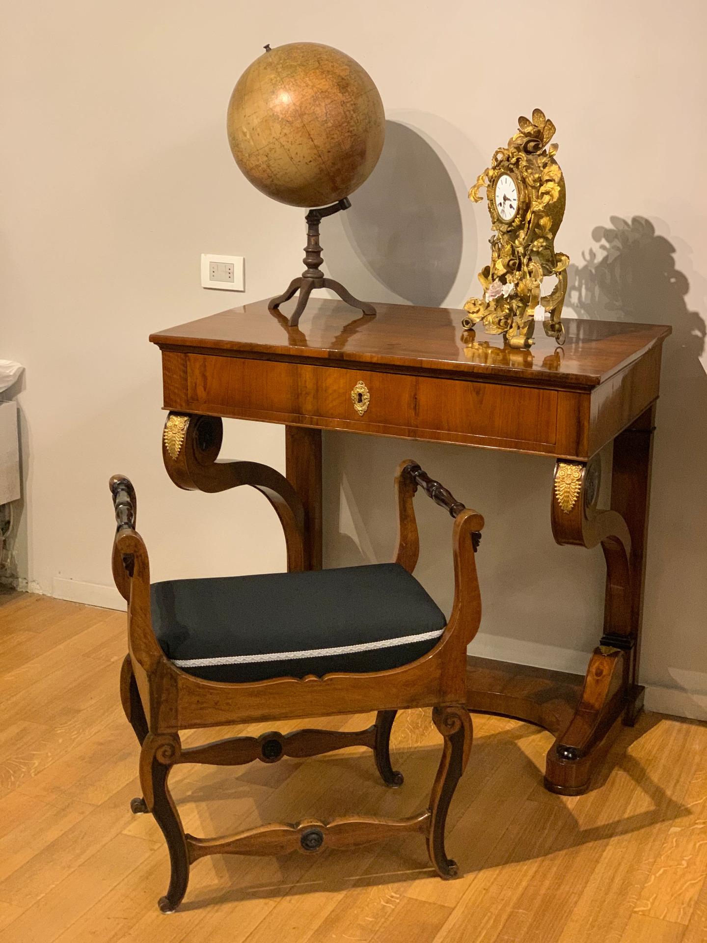 Elegant console veneered in blond walnut and polished with two colors on some carved solid wood details, embellished with gilt bronze palmette friezes.
A detail of the structure are the stylized cornucopias that act as supporting columns that