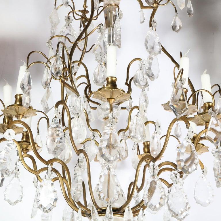 This elegant rock crystal and gilded bronze nine-arm chandelier was realized in France, during the early 19th century. It features a central baluster body carved in rock crystal from which nine sinuously curved gilded bronze arms extend culminating