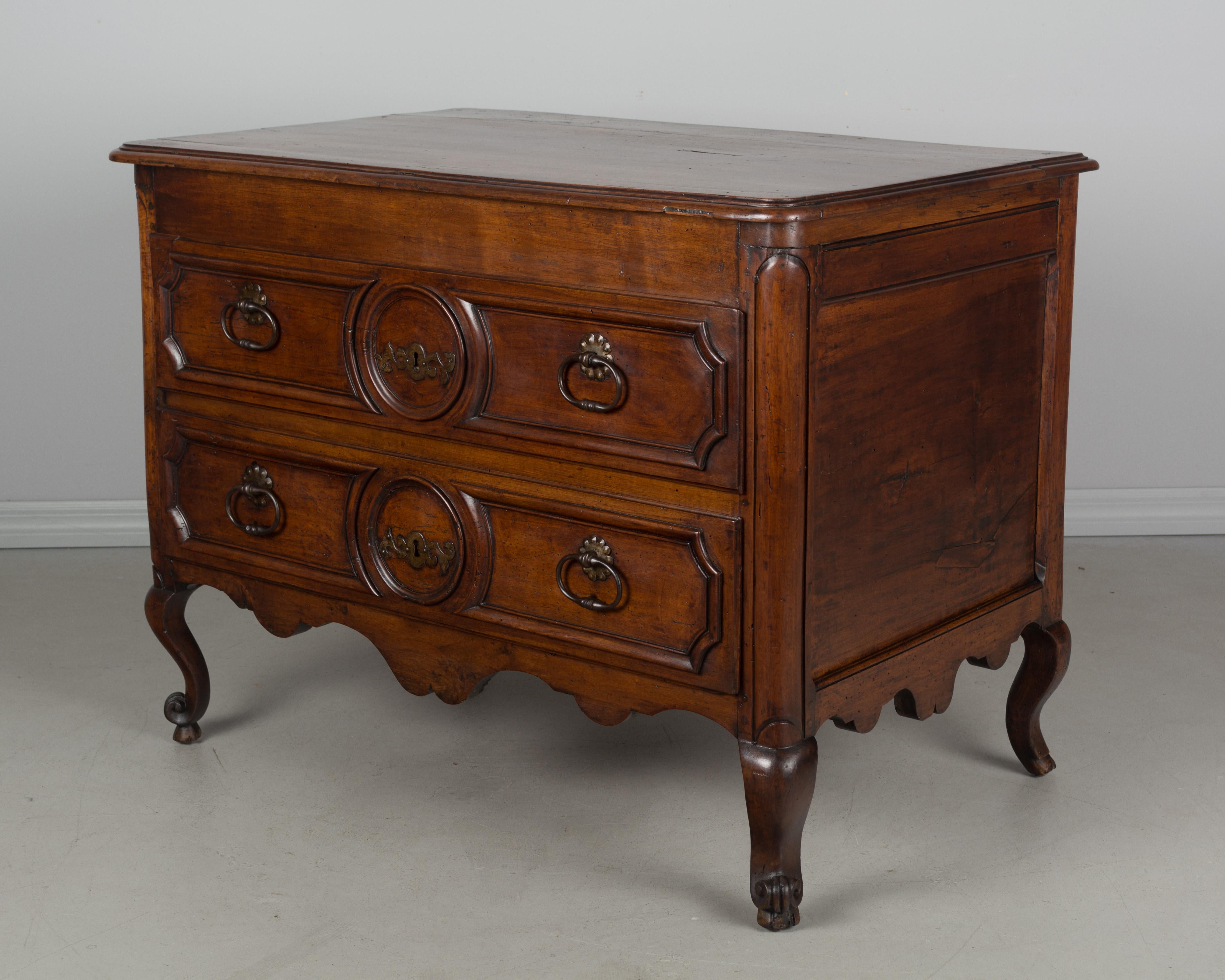 A Louis XV style French commode, or chest of drawers, made of solid hand carved walnut and finished on all four sides. Beautiful quality to the wood with a waxed patina. This chest was converted from a blanket chest in the 19th century. Two