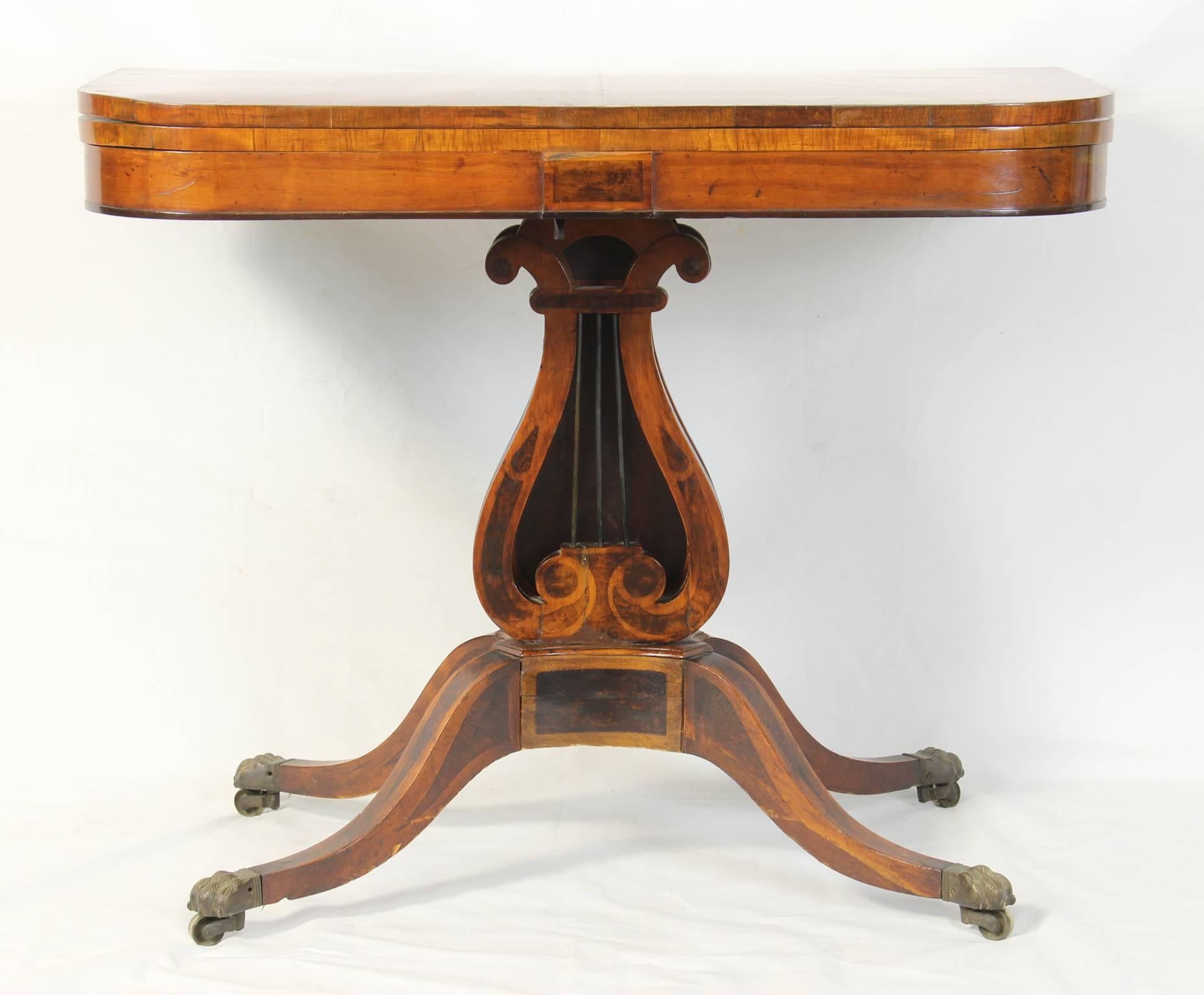 An elegant early 19th century. English mahogany and satinwood card table with large Lyre shaped pedestal on saber legs and brass cap casters.