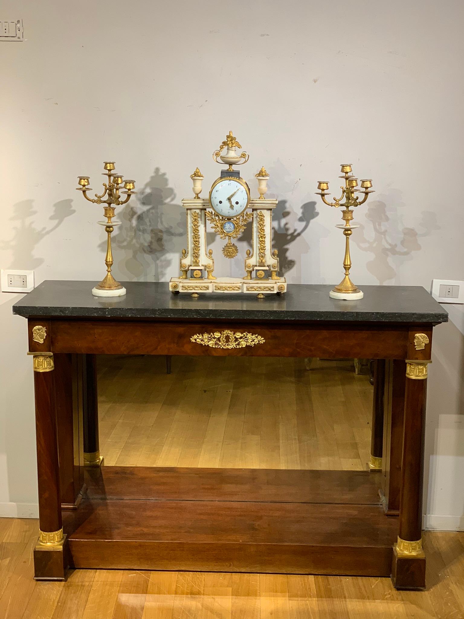 Beautiful console veneered in mahogany with columns ending with Corinthian capitals chiselled in gilded mercury bronze. A drawer in the band embellished with a stupendous bronze frieze en pendant with the two classic profiles above the columns. The
