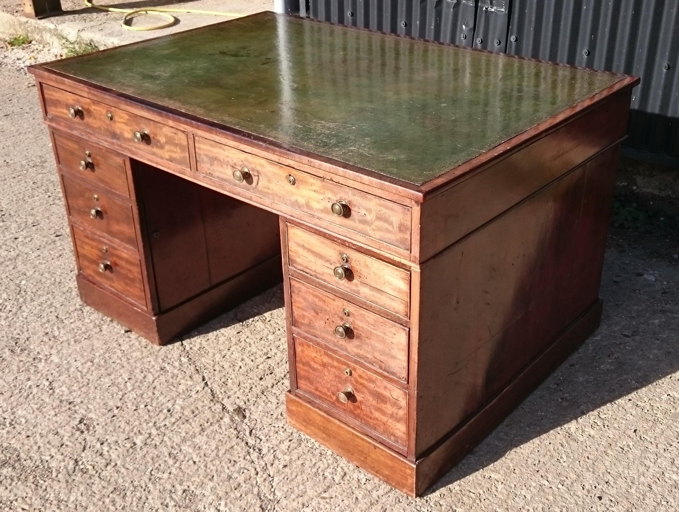 Early 19th century pedestal desk with five drawers and one cupboard on one side. The cupboard is disguised with false drawer fronts. The other side of the desk is finished with mahogany but does not have dummy drawers. Because it does not have
