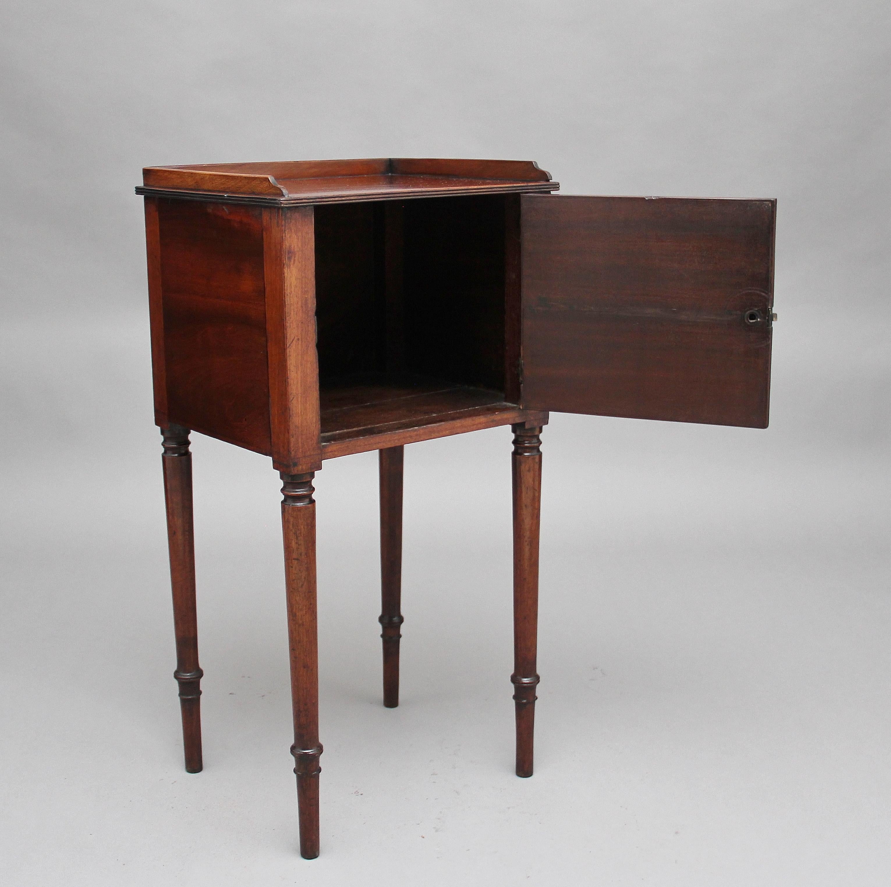 Early 19th century mahogany bedside cabinet, having a three a quarter gallery top above a hinged door raised on round turned legs, circa 1810.